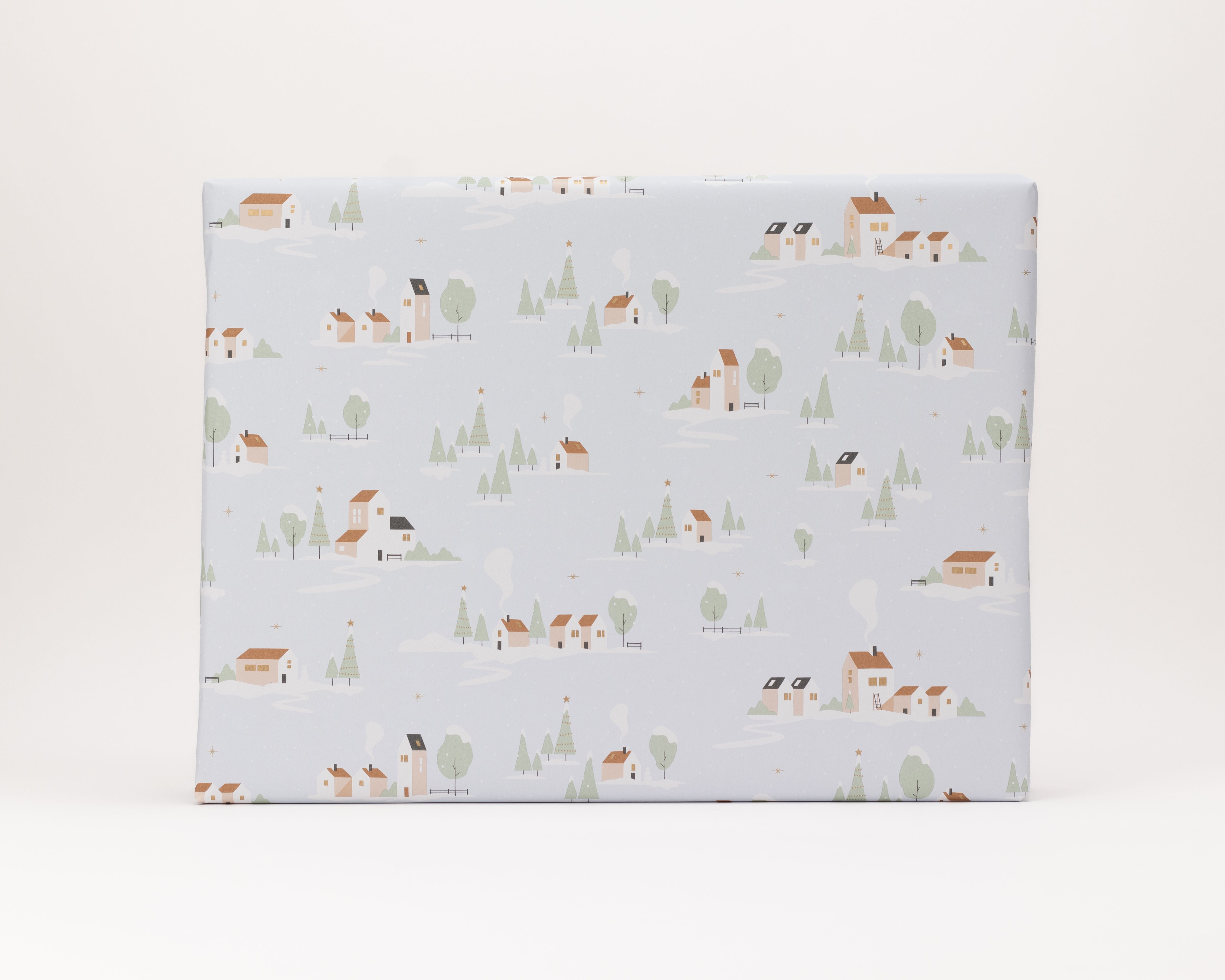 Geschenkpapier-Set mit einem Muster aus einem stilisierten Winterdorf auf hellblauem Hintergrund mit Häusern in Weiß- und Terrakotta-Tönen
