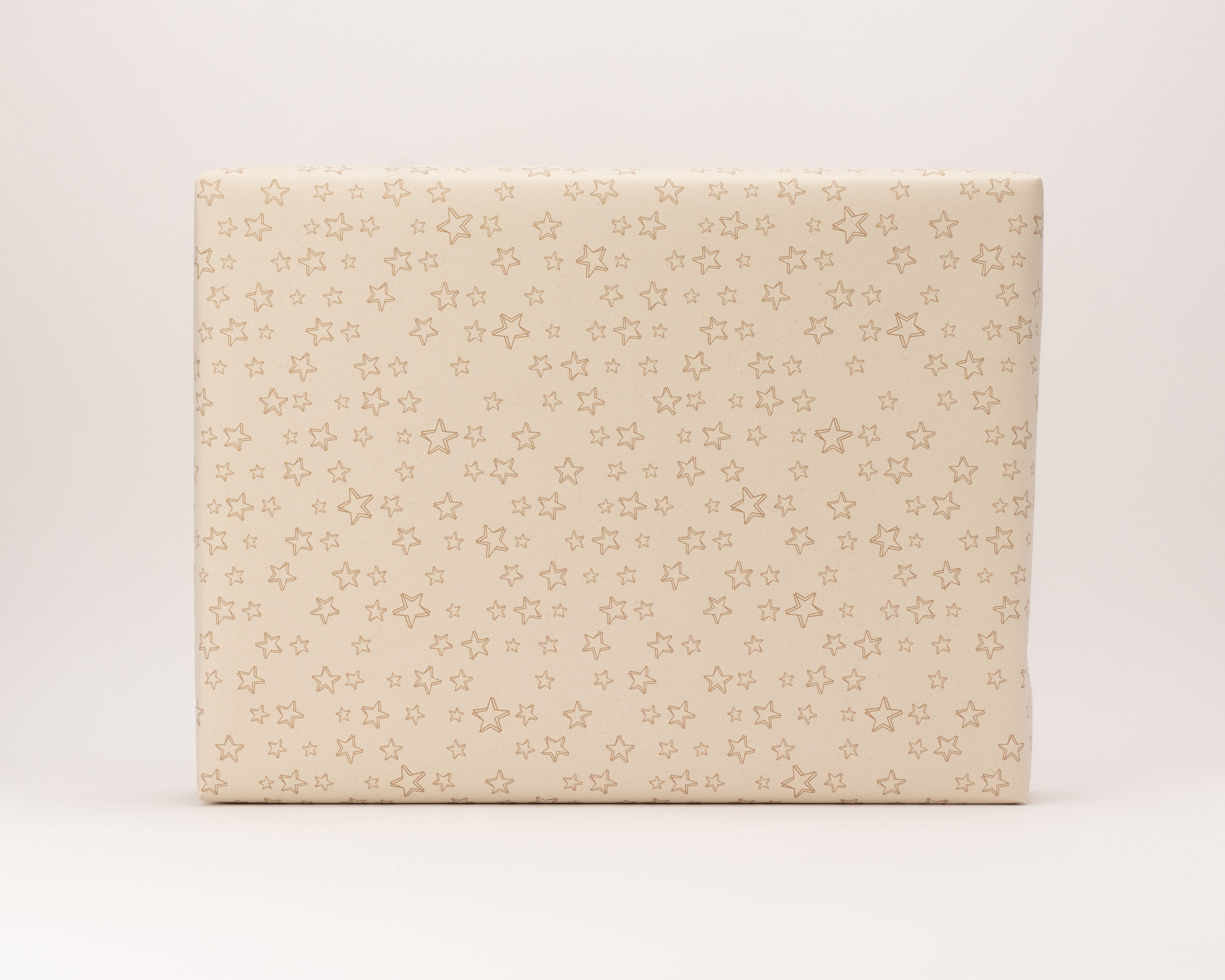 Geschenkpapier-Set, ein eingepacktes Geschenk in hellem Kraftpapier mit wiederholten goldenen Sternenmustern