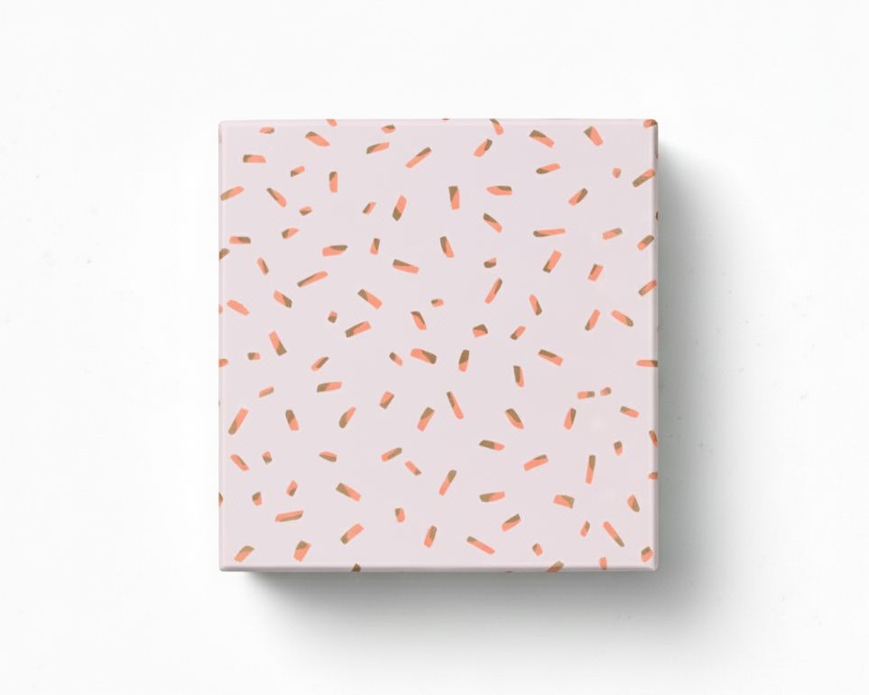Geschenkpapier mit einem Sprinkles-Muster in hellem Flieder, Gold und Neon Orange, als verpacktes Geschenk von oben gezeigt