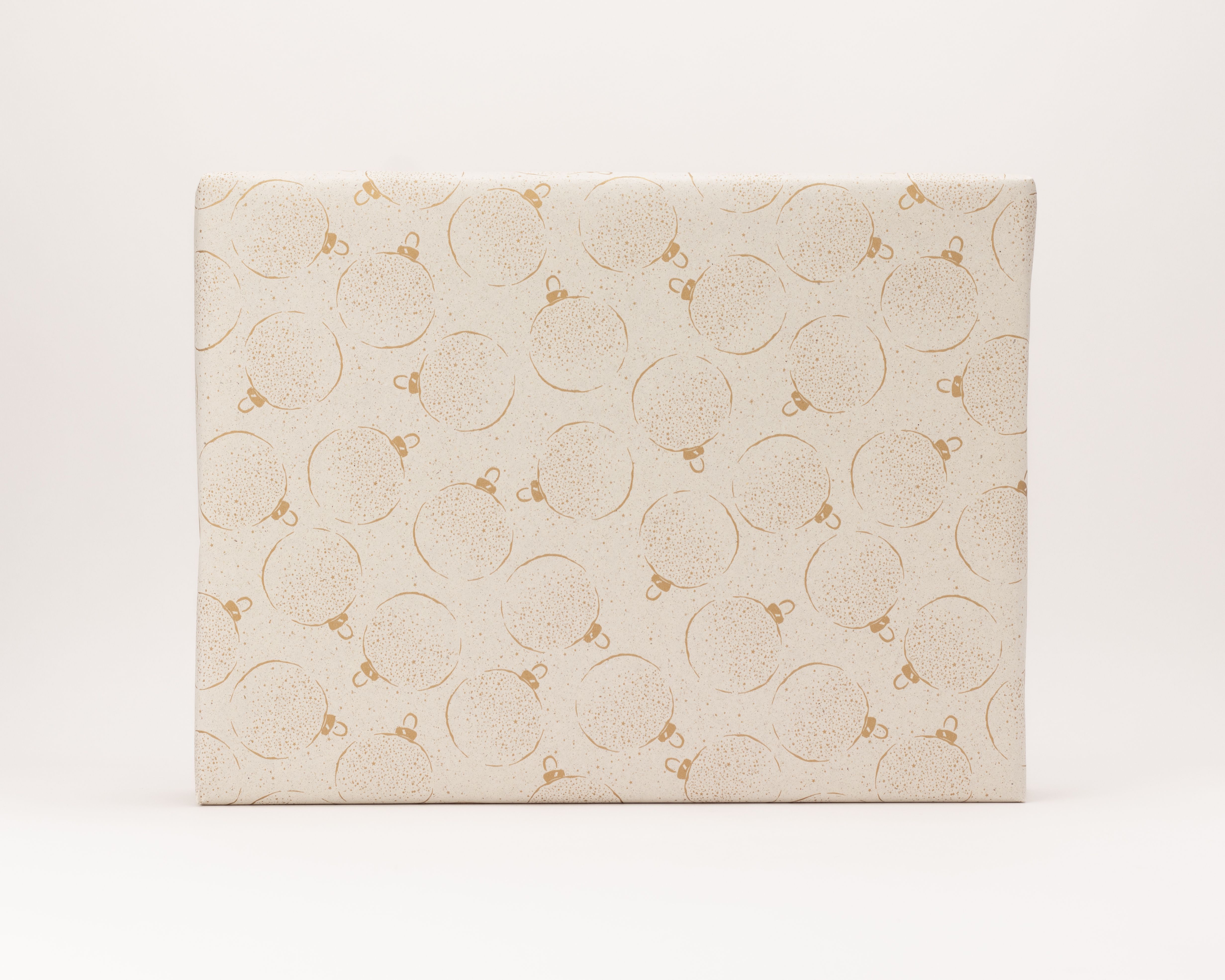 Geschenkpapier-Set mit hellem Graspapier, das ein Muster aus goldenen Weihnachtskugeln zeigt.
