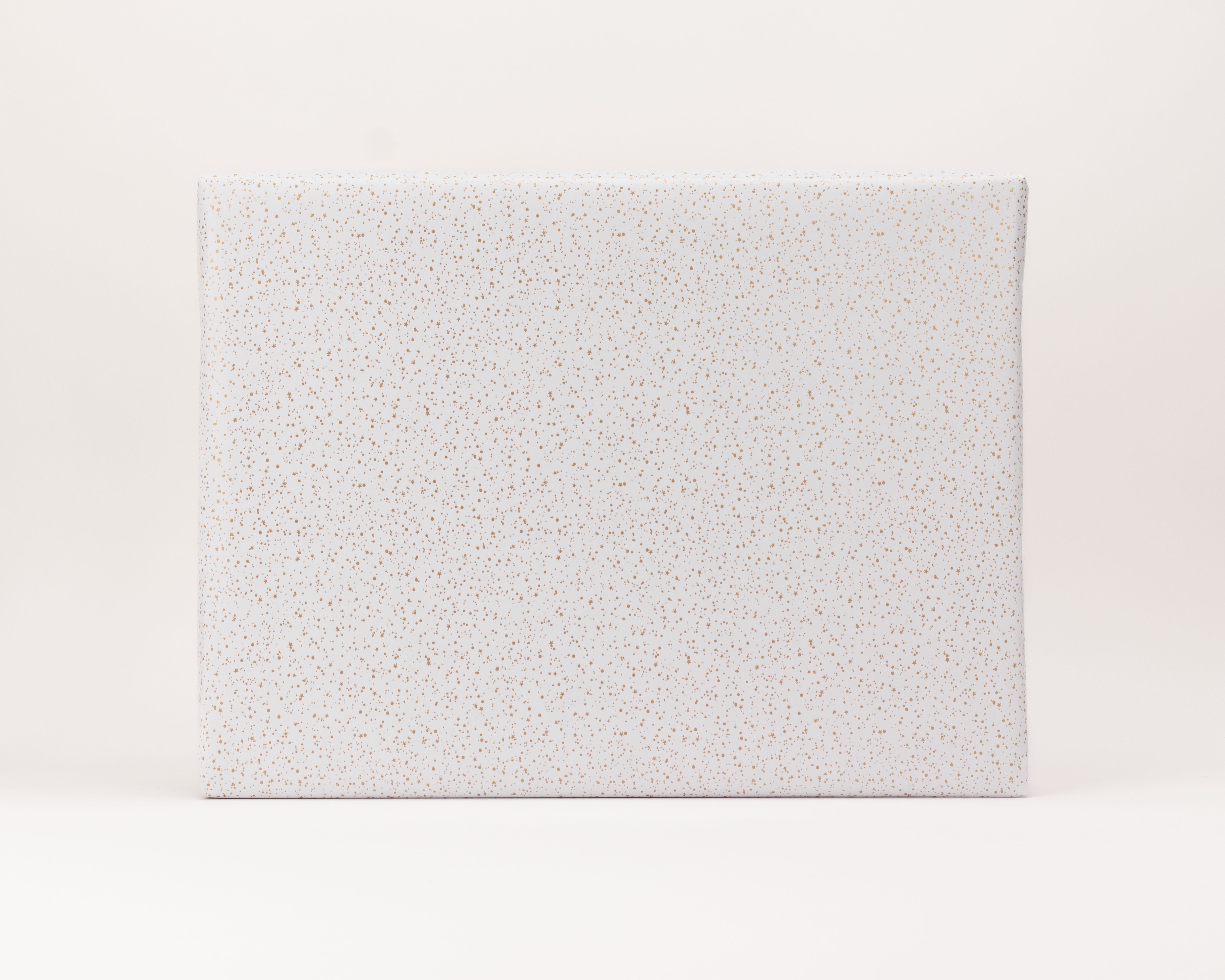 Geschenkpapier-Set mit einem Geschenk, eingepackt in weißes Papier mit goldenen Sternen und Punkten