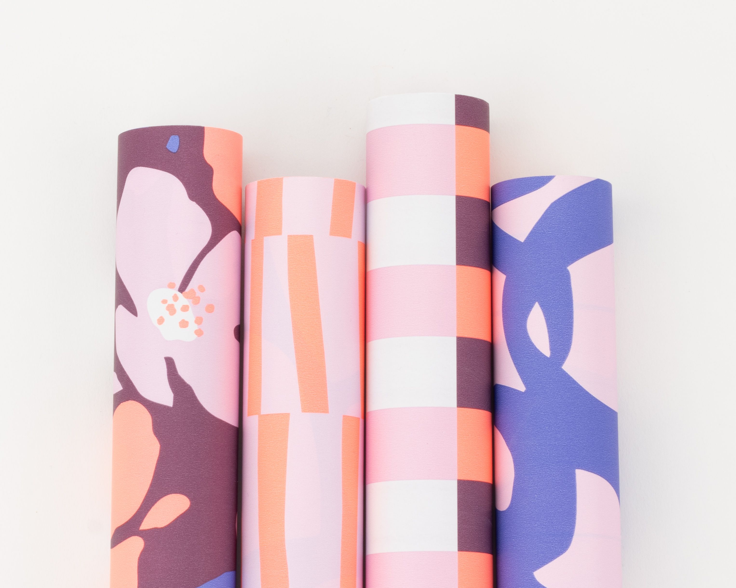 Geschenkpapier-Set mit vier Rollen in lebhaften Farbtönen wie Plum, Orange, Flieder und Blau mit floralen und grafischen Mustern