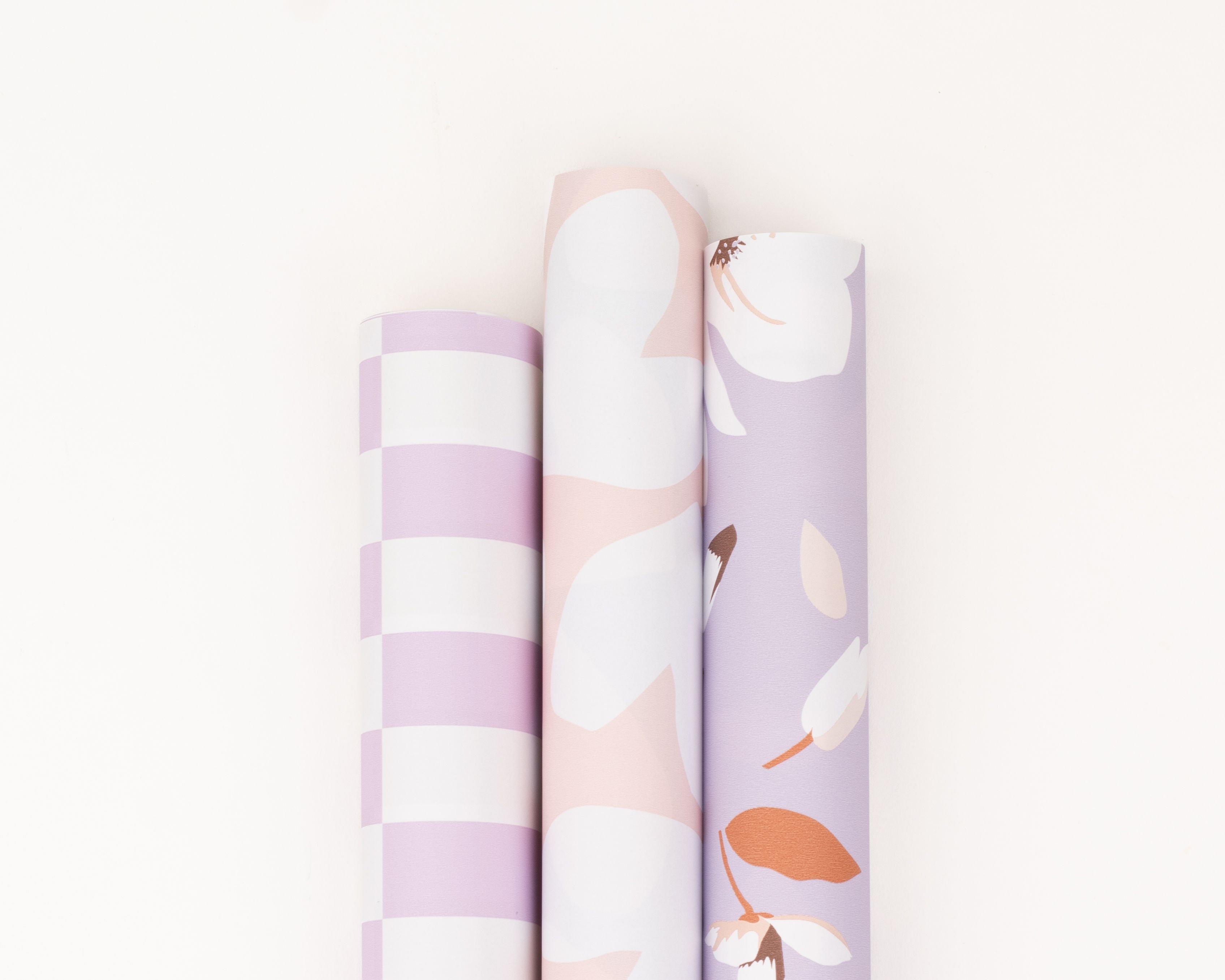 Geschenkpapier-Set mit drei Rollen in Flieder, Hellflieder, Rosa und Weiß. Die Muster zeigen Blockstreifen, Herzen und Magnolienblüten