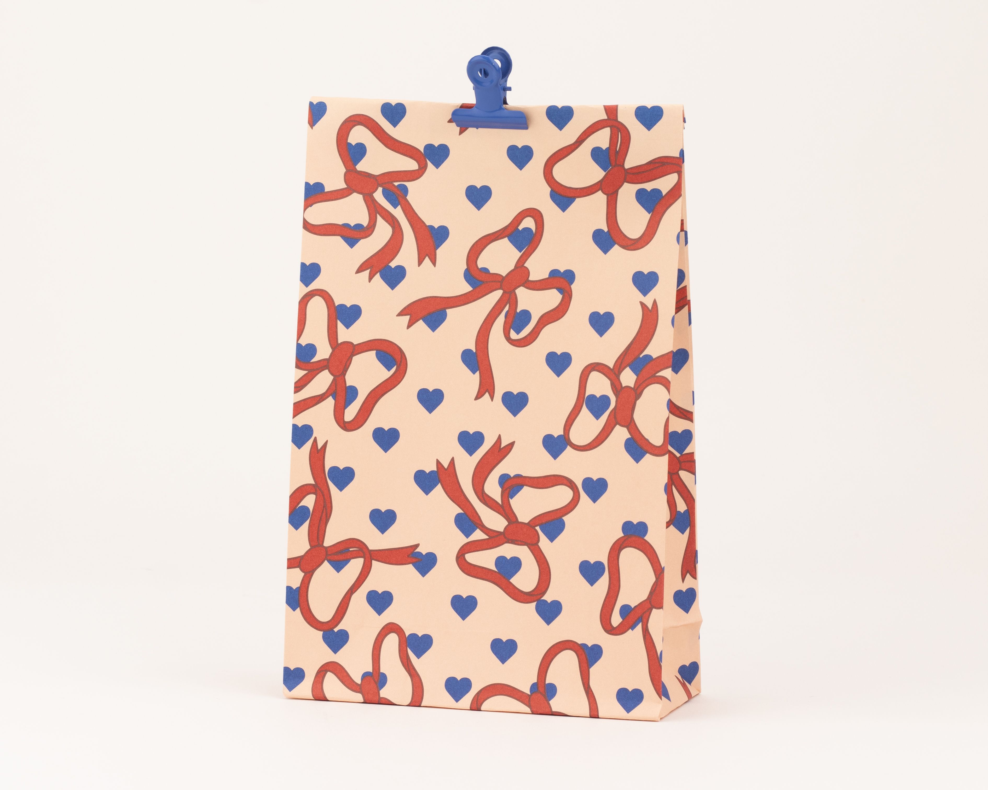Papiertüten Blockbodenbeutel in pfirsich mit einem Muster aus roten Schleifen und kornblumenblauen Herzen