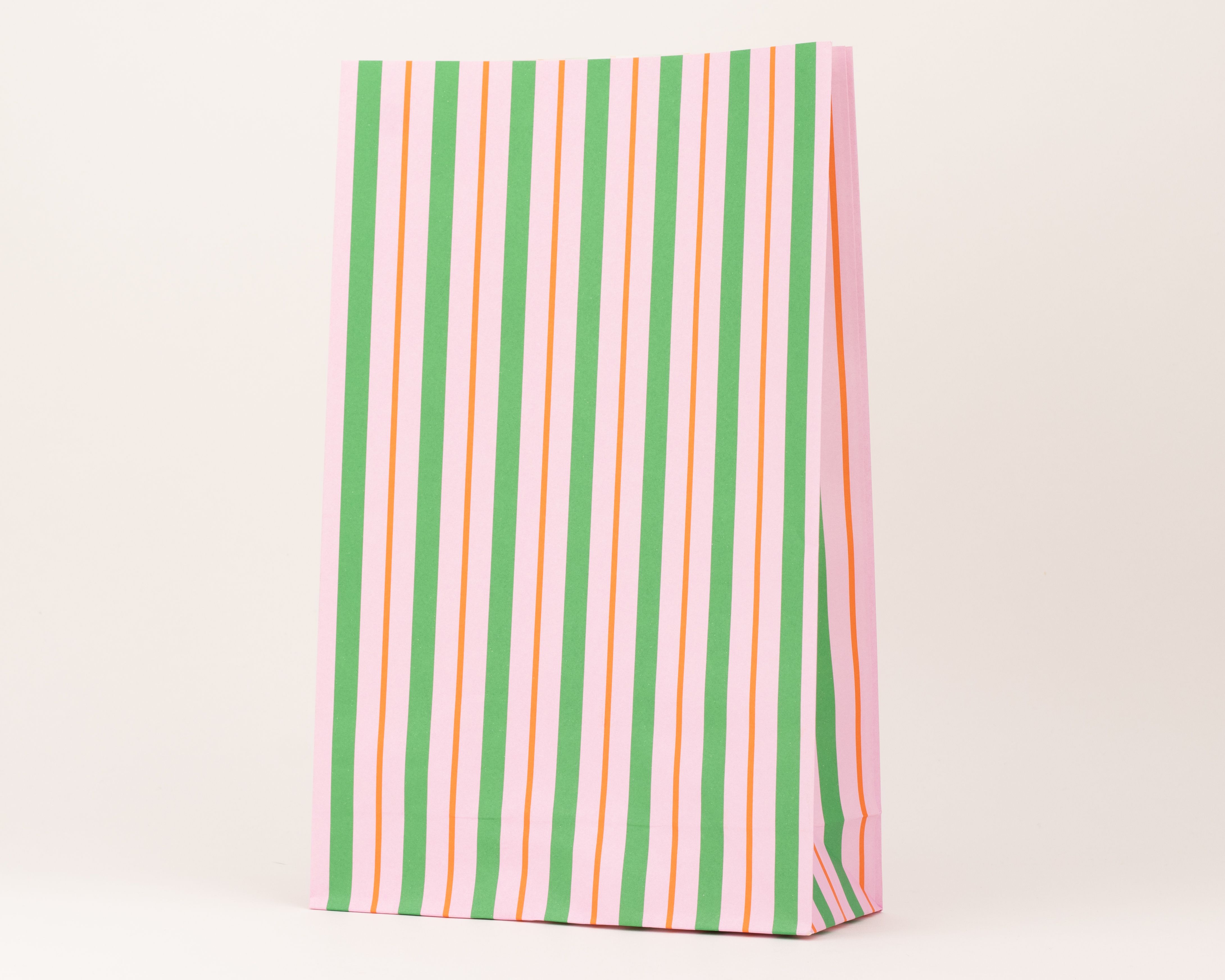 Papiertüten Blockbodenbeutel zeigen ein vertikales Streifenmuster in Rosa, Rotorange und Grün und stehen stabil auf ihrem rechteckigen Boden