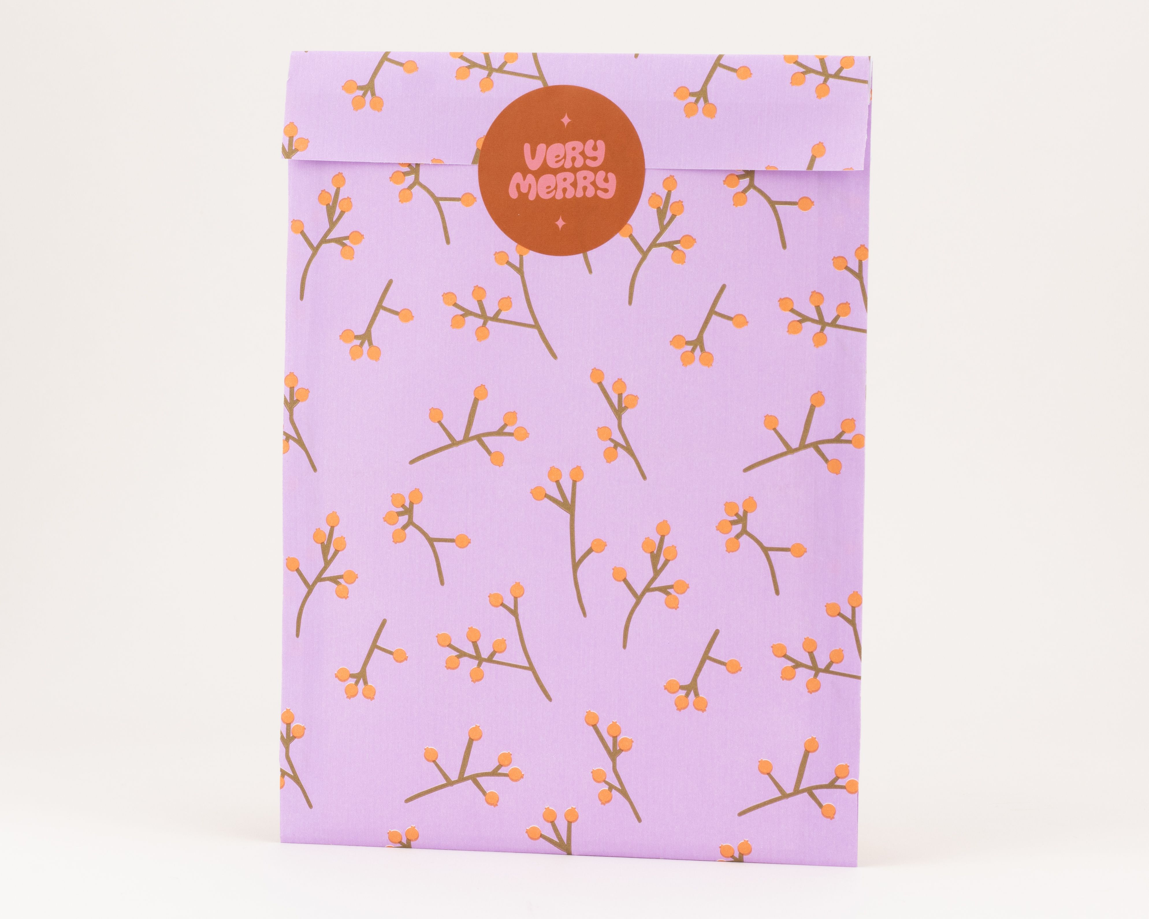 Flachbeutel in Flieder mit Beerenrankenmuster aus Braun und Kaki-Orange, mit rundem braunen Sticker versiegelt, Innenseite reinweiß.
