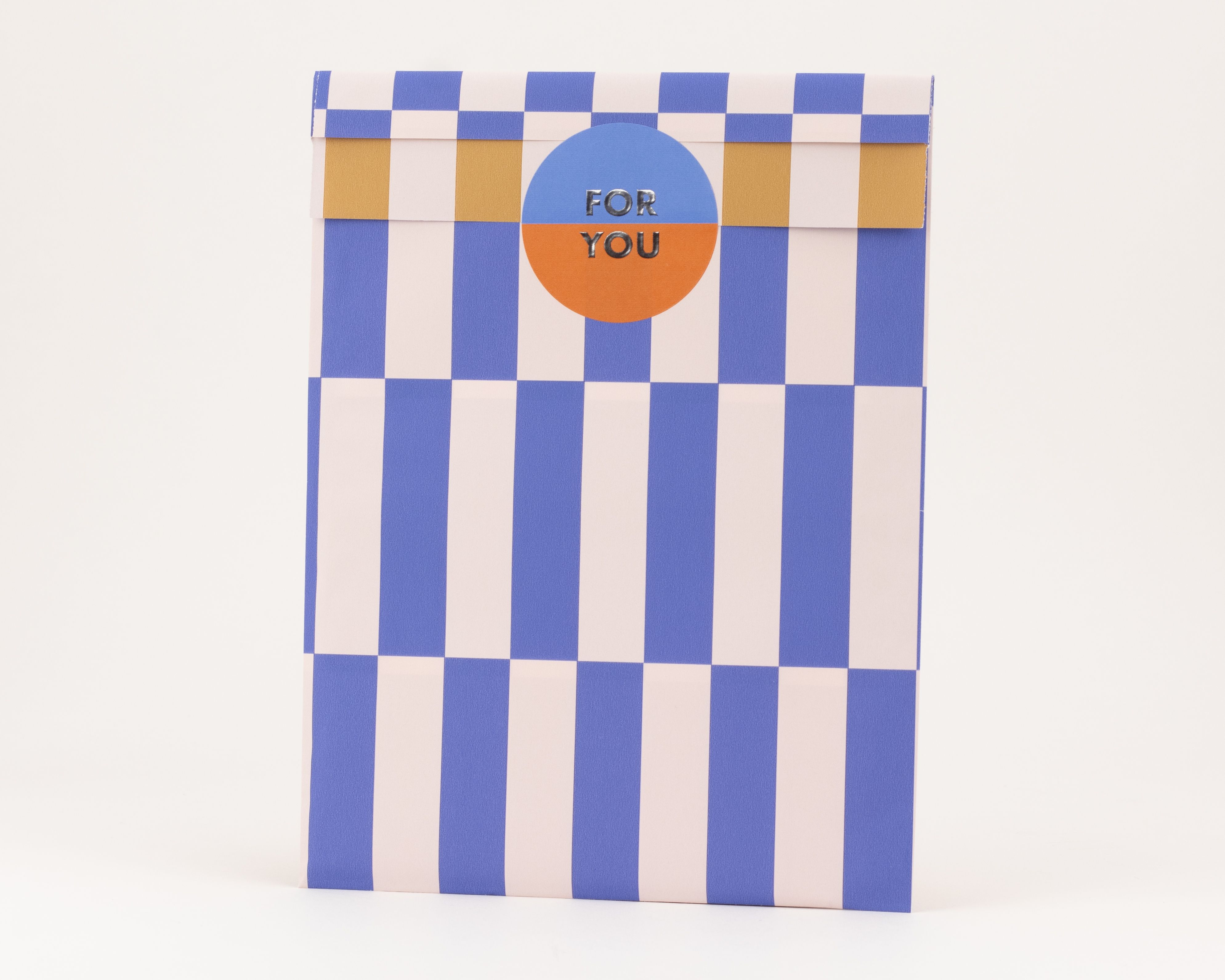 Flachbeutel mit einem markanten Bold Stripes Muster in Blau und Elfenbein. Die Innenseite zeigt ein auffälliges Ocker Blockmuster