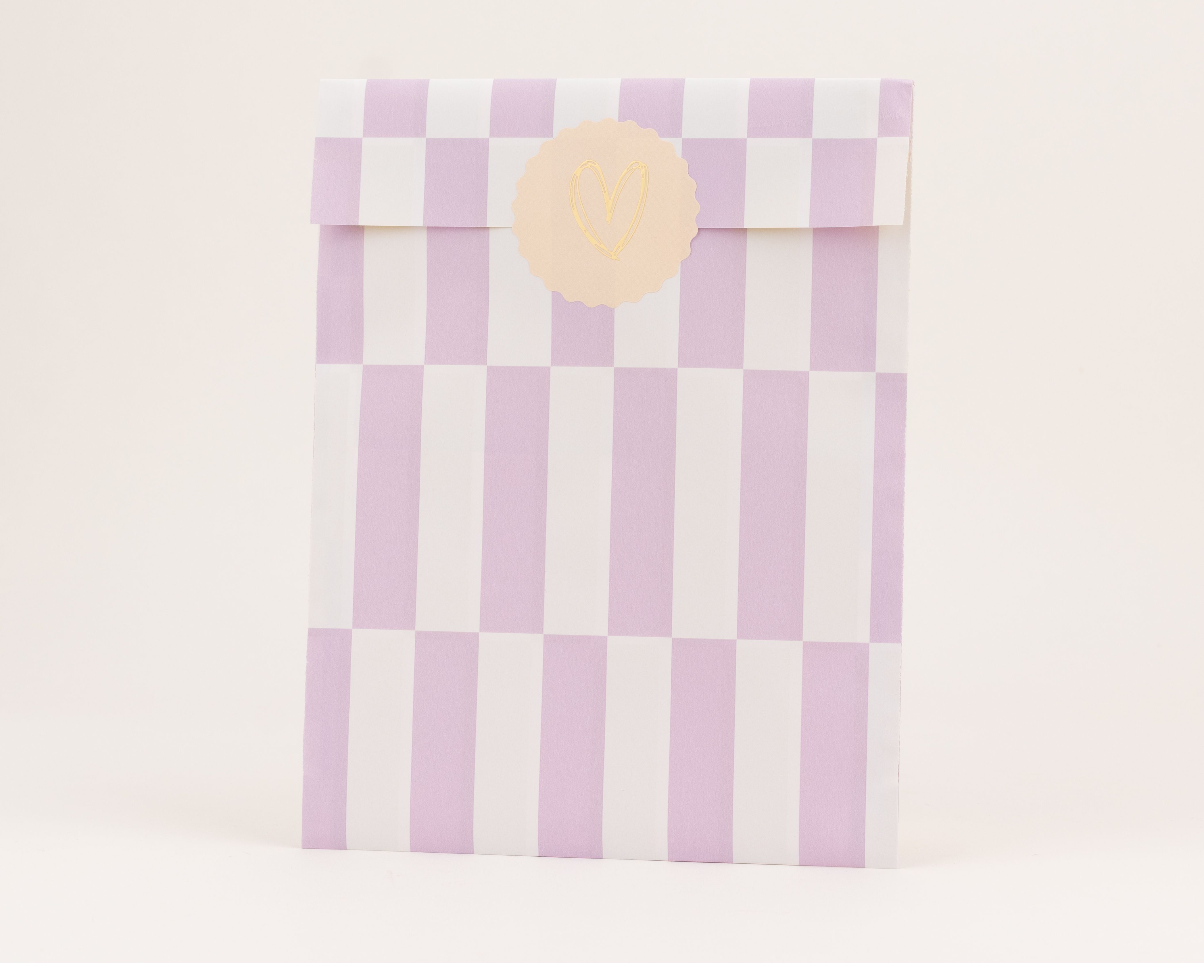 Flachbeutel mit Flieder und Weiß gestreifter Oberfläche und karierter Innenseite, dazu ein runder gelber Herzsticker