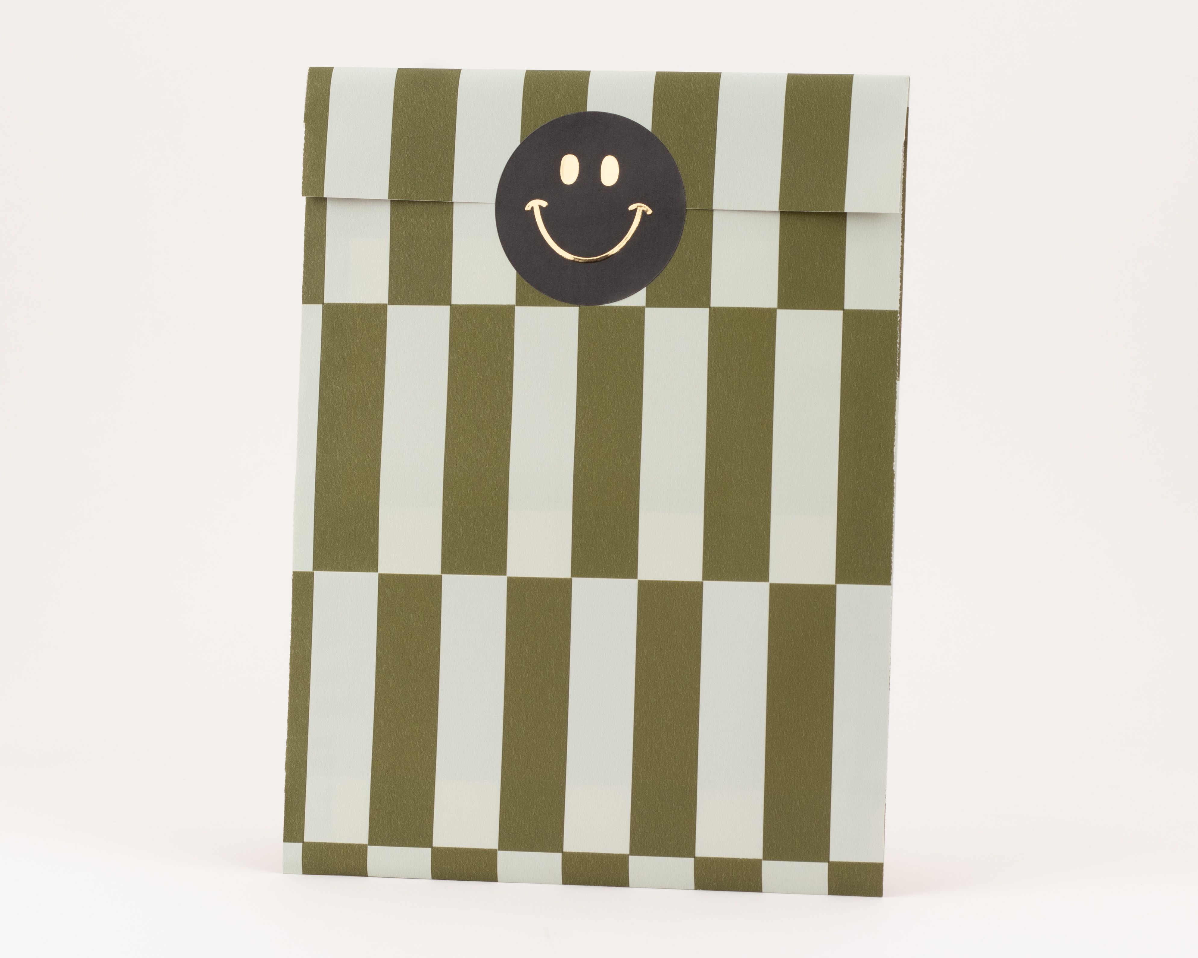 Flachbeutel mit markanten vertikalen Streifen in Olivgrün und Salbeigrün, oben verschlossen mit einem schwarzen Smiley-Sticker