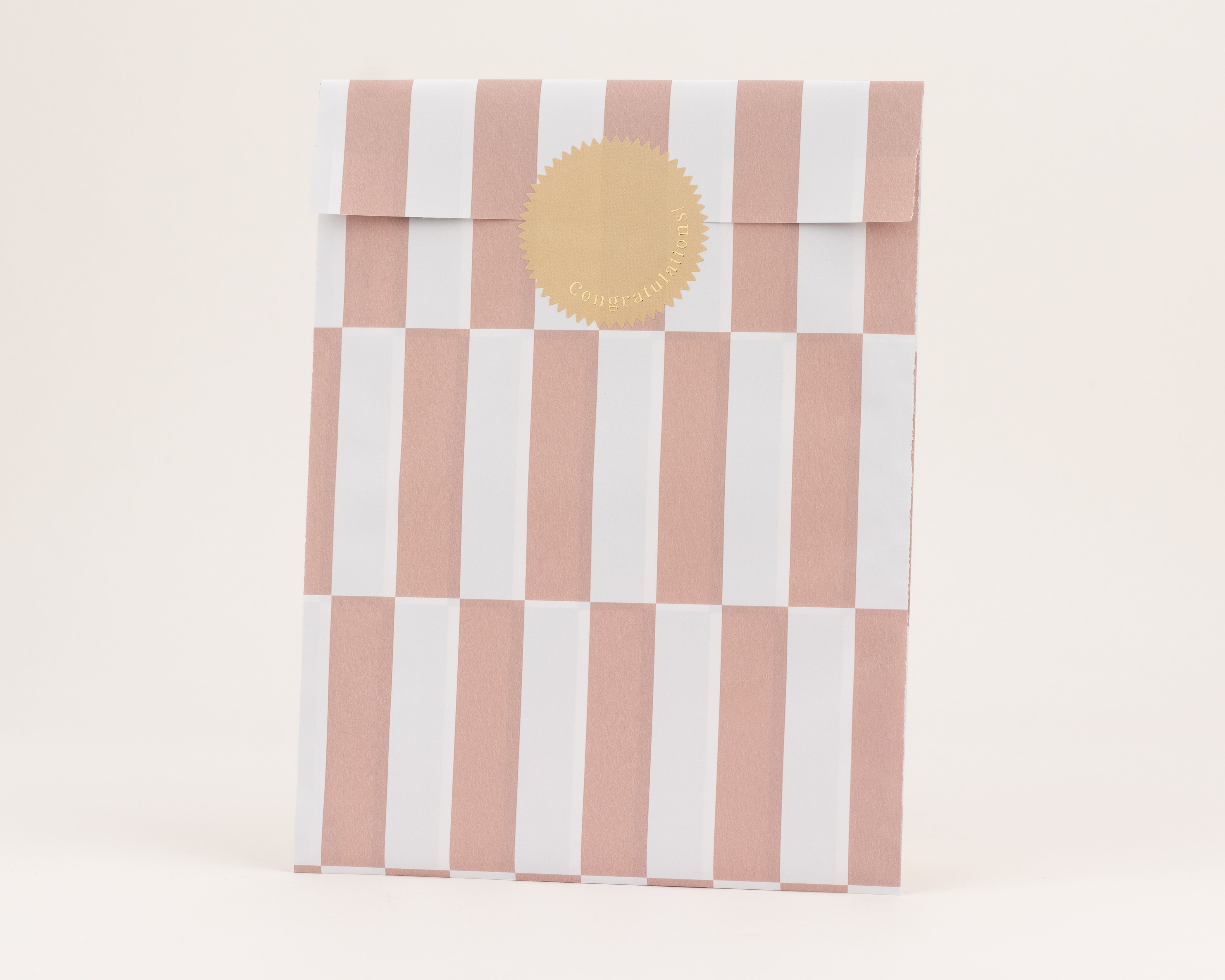 Papiertüten mit markanten rosa und weißen Streifen auf der Außenseite und der Innenseite, verziert mit einem braunen Goldsticker