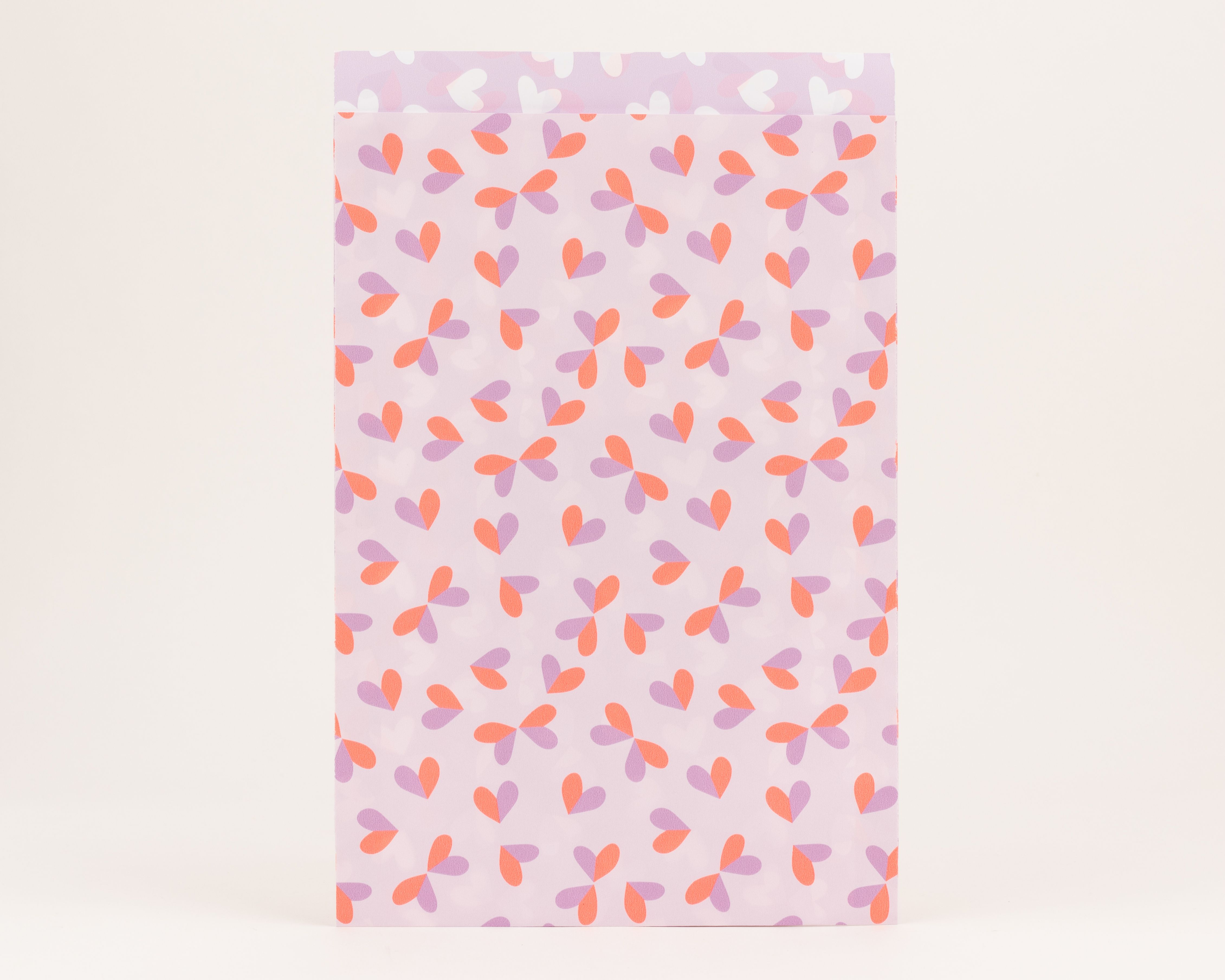Flachbeutel mit Herzmuster in Hellflieder und Neon Orange. Die Innenseite ist hellfliederfarben mit einem dezenten Muster aus weißen Herzen