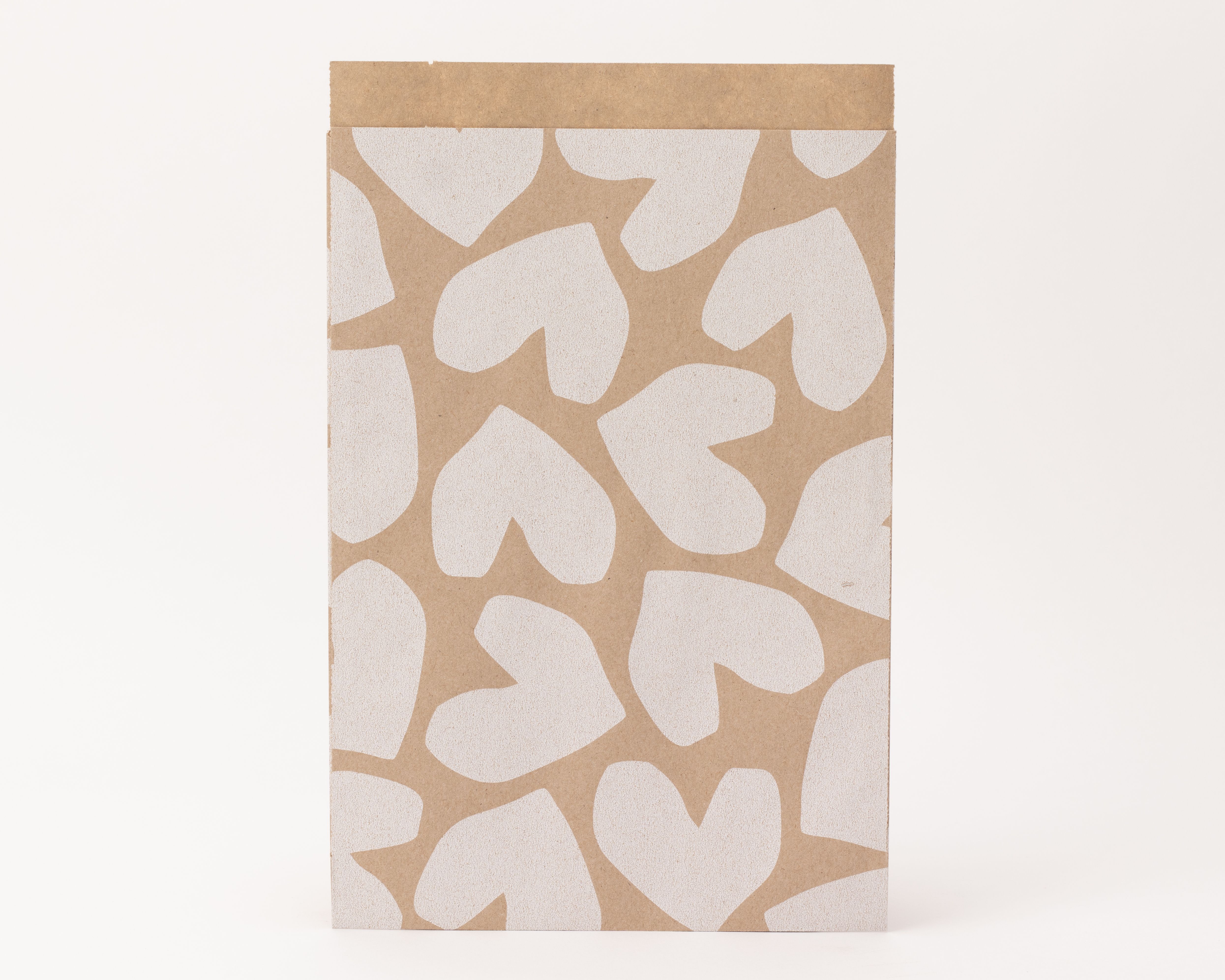 Flachbeutel mit einem Muster aus weißen Herzen auf kraftfarbenem Papier und einer unifarbenen kraftfarbenen Innenseite