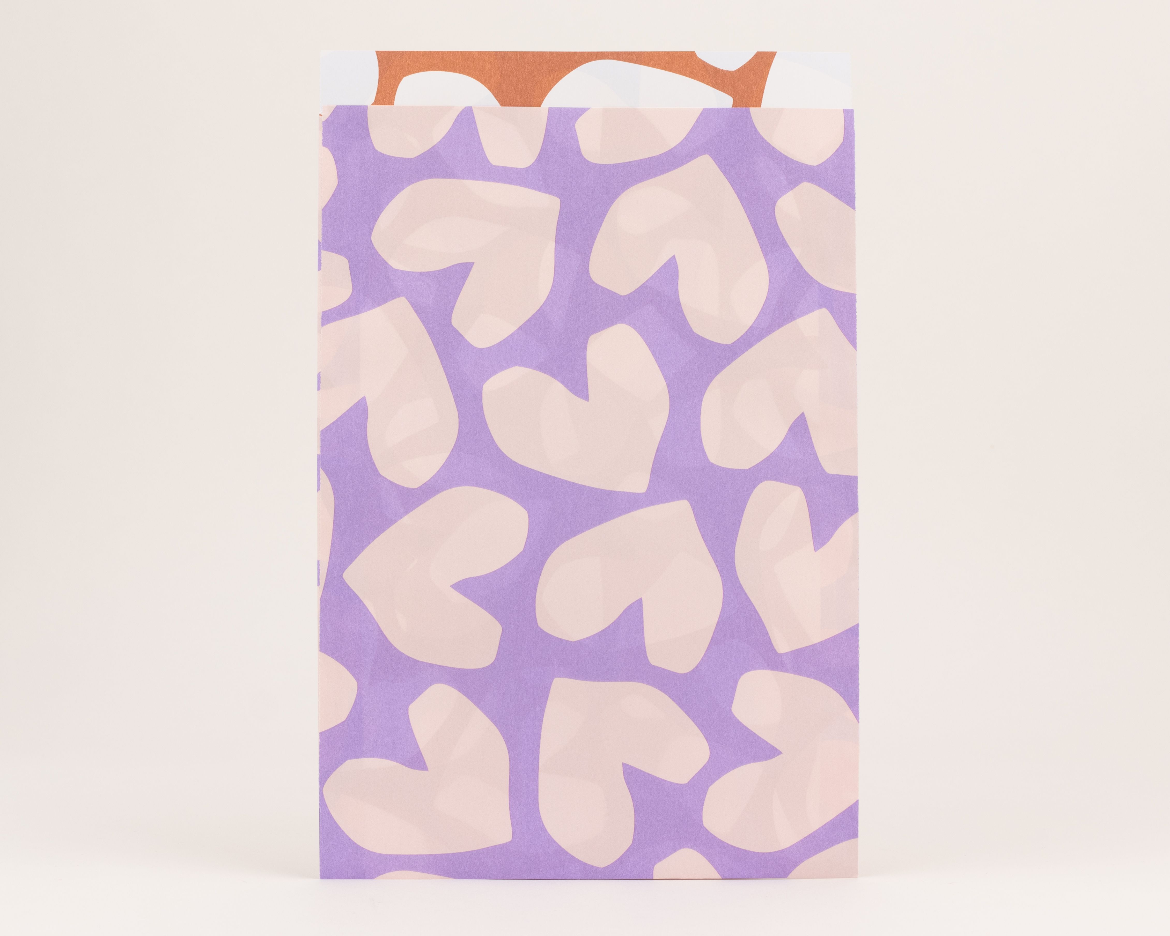 Flachbeutel mit lila Außenseite und hellfliederfarbenen Herzen, die Innenseite ist rostfarben