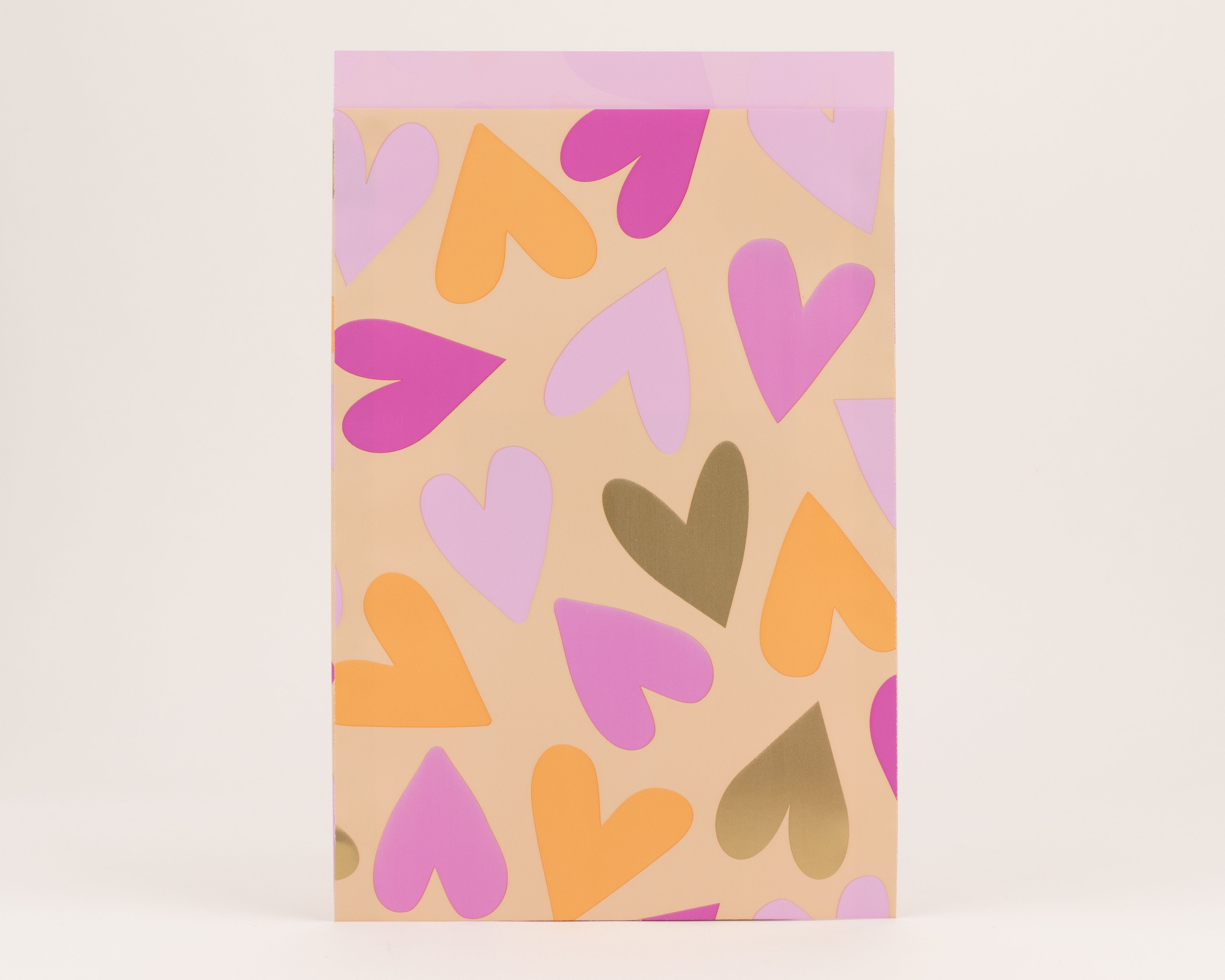 Flachbeutel mit einem pfirsichfarbenen Hintergrund und Herzen in Orange, Pink und Gold, die Innenseite ist hellrosa