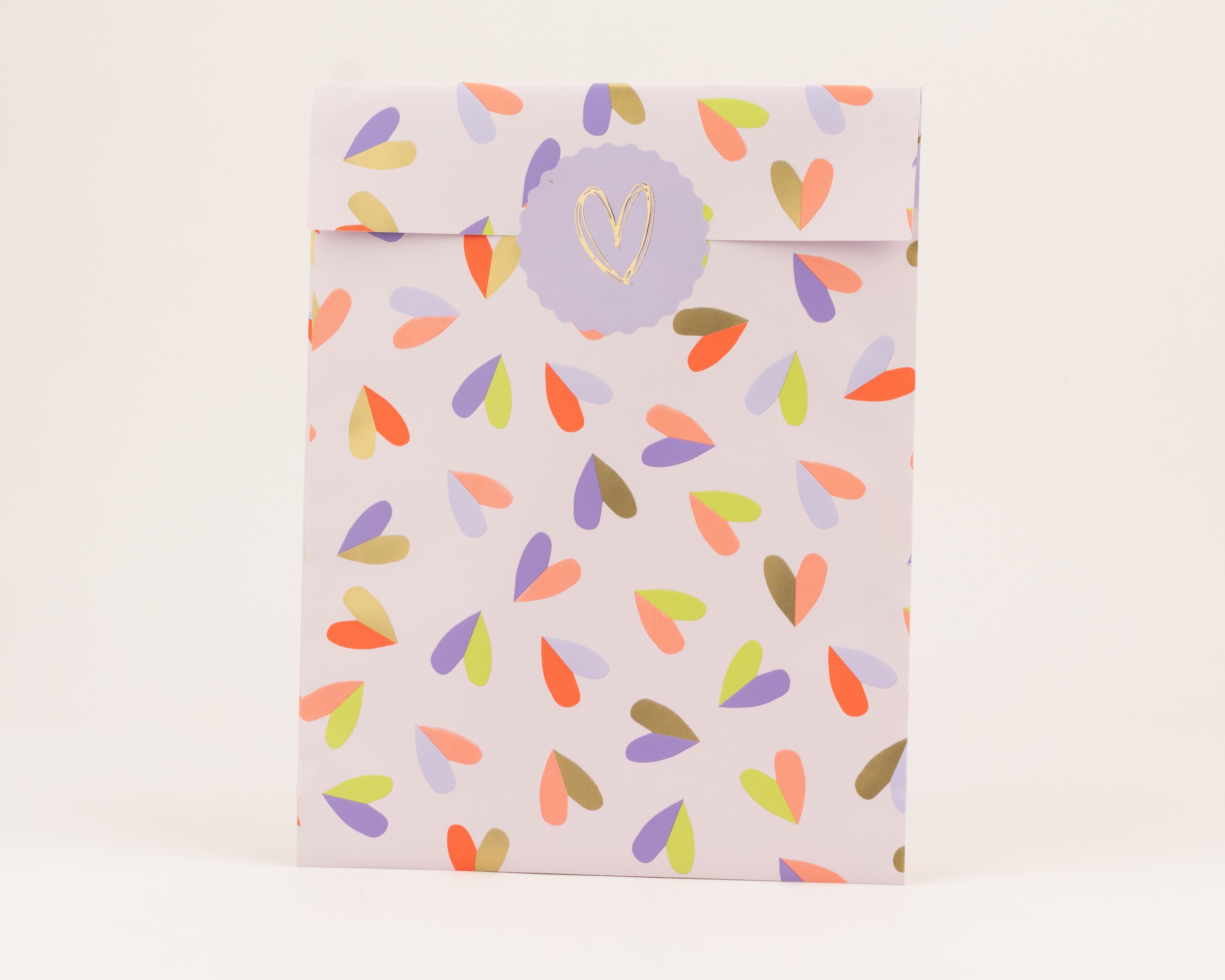 Flachbeutel in Flieder mit einem bunten Herzmuster in Orange, Violett, Limettengrün und Hellviolett. Die Innenseite ist Flieder.