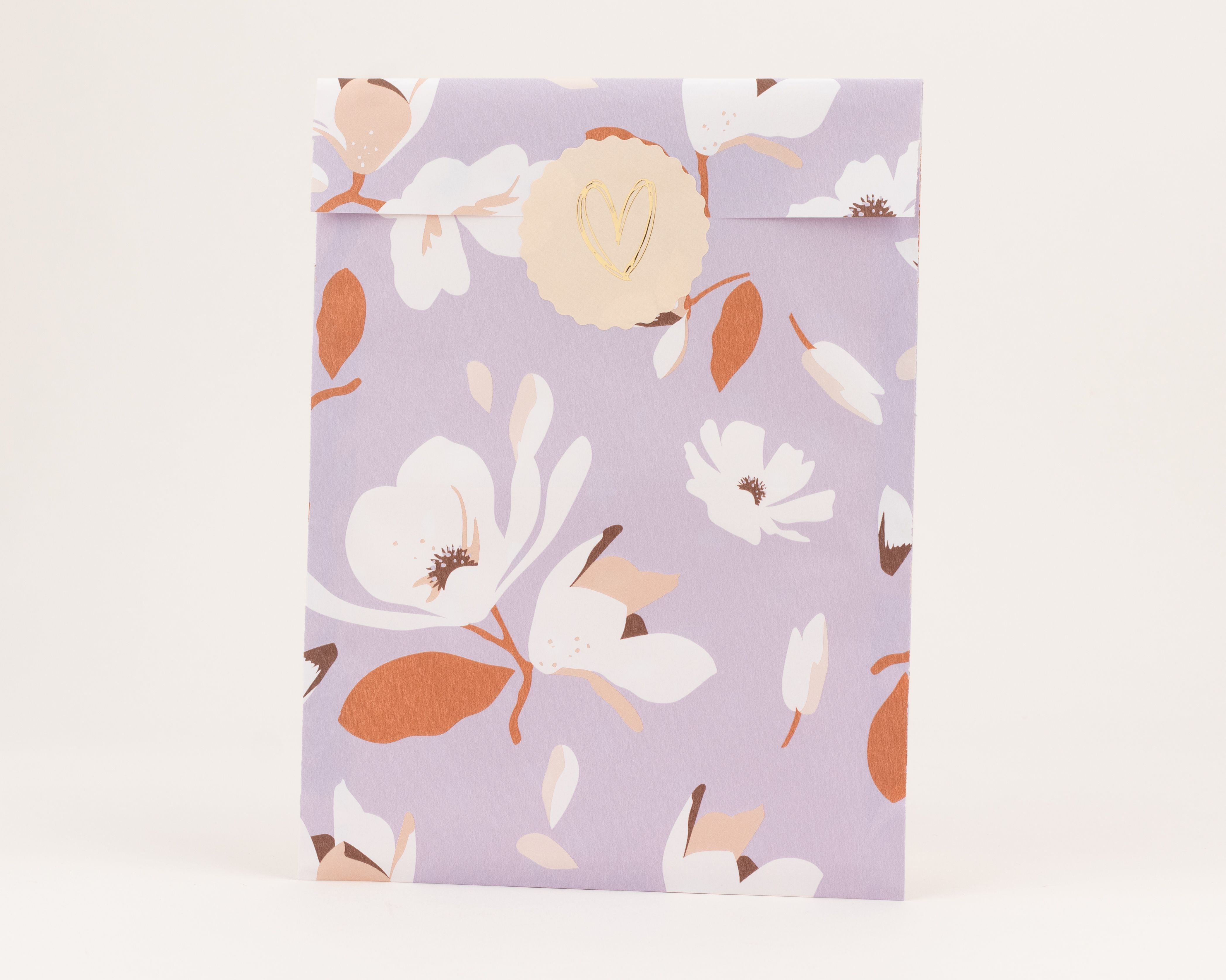 Flachbeutel mit fliederfarbenem Hintergrund und Magnolienmuster in Weiß, Rost und Beige. Die Innenseite zeigt dasselbe Design