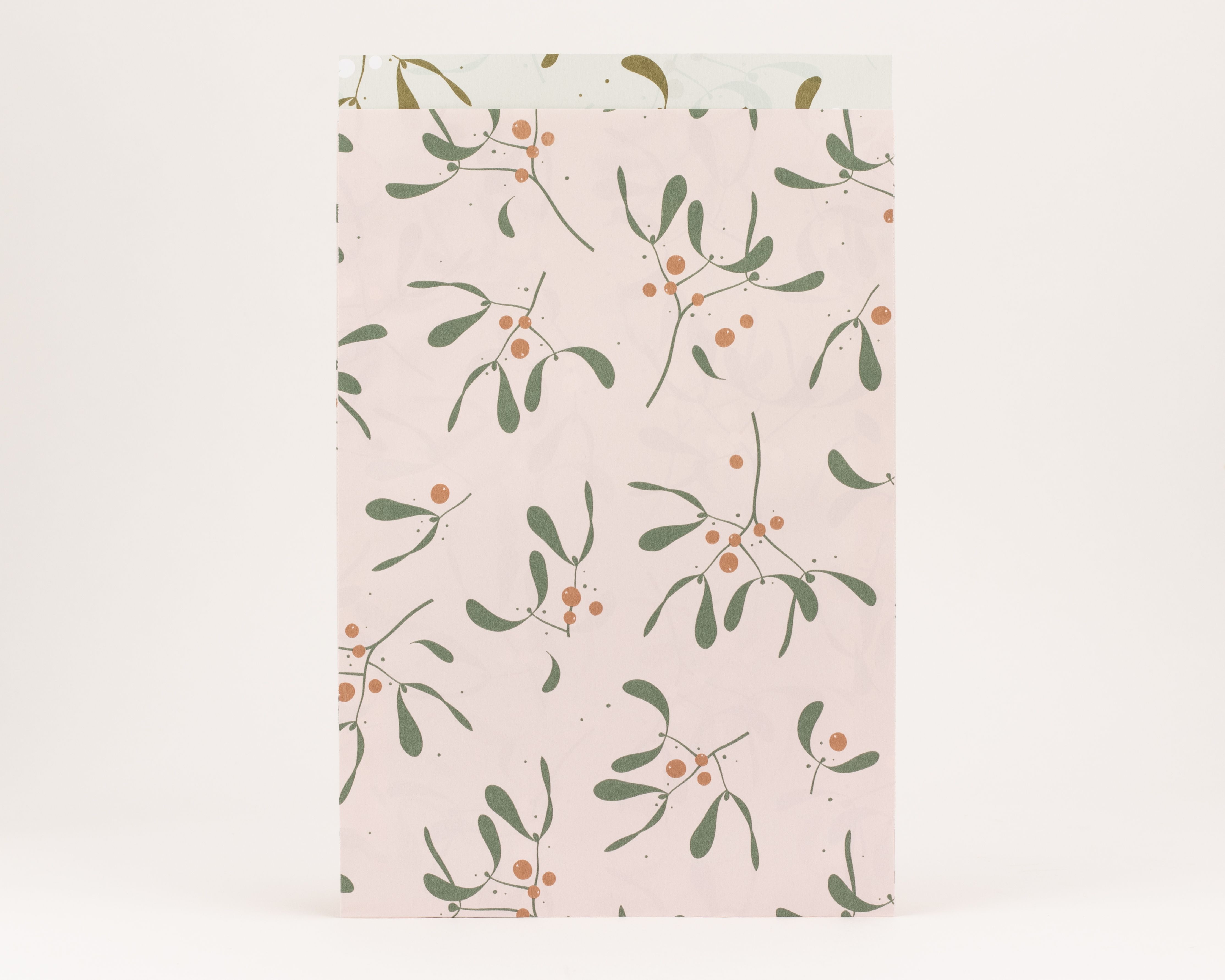 Flachbeutel mit rosafarbener Außenseite, bedruckt mit olivgrünen Mistelzweigen und zimtfarbenen Beeren. Die Innenseite ist hell olivgrün