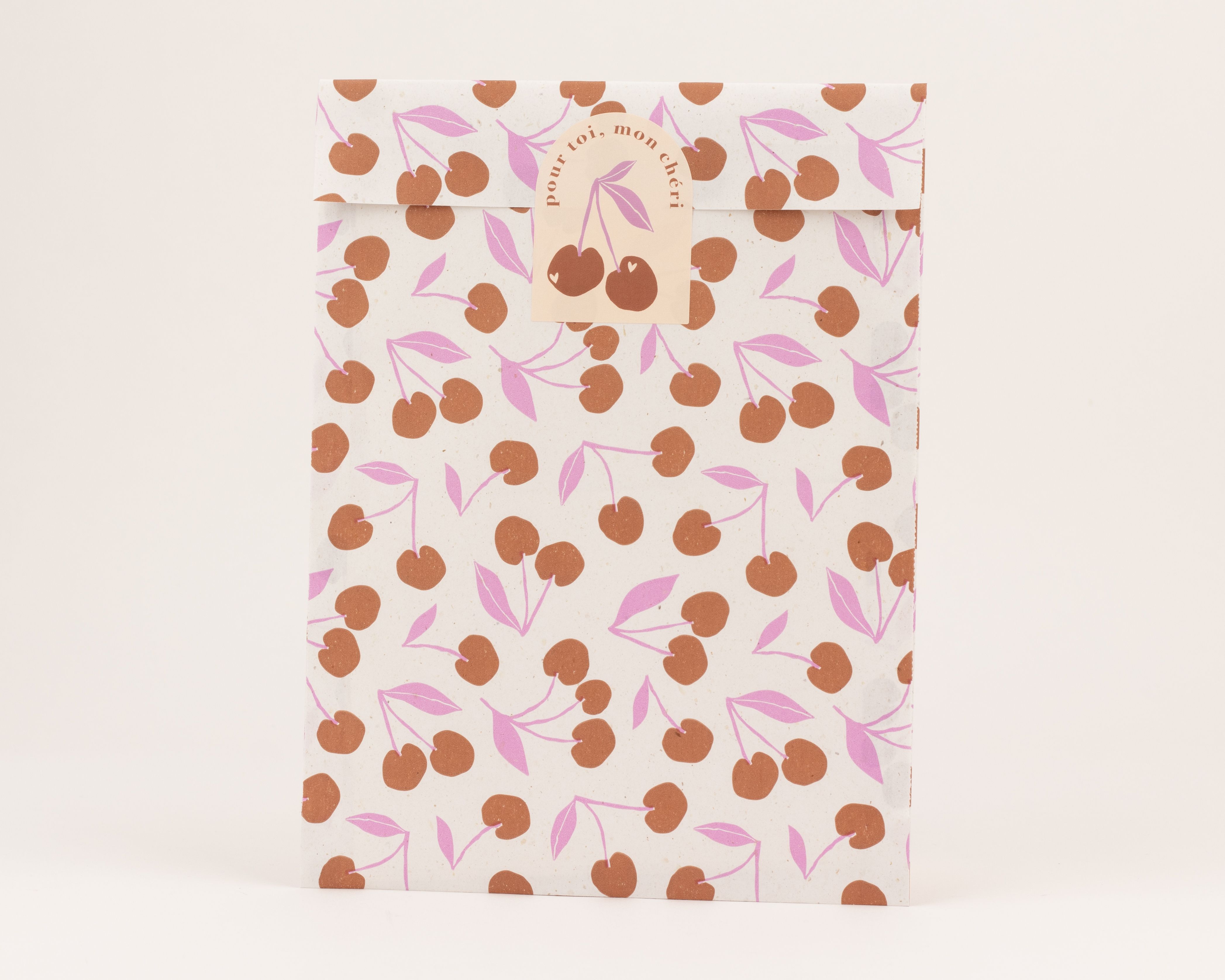 Flachbeutel mit einem Retro Kirschenmuster in Braun und Pink auf einem hellen Hintergrund
