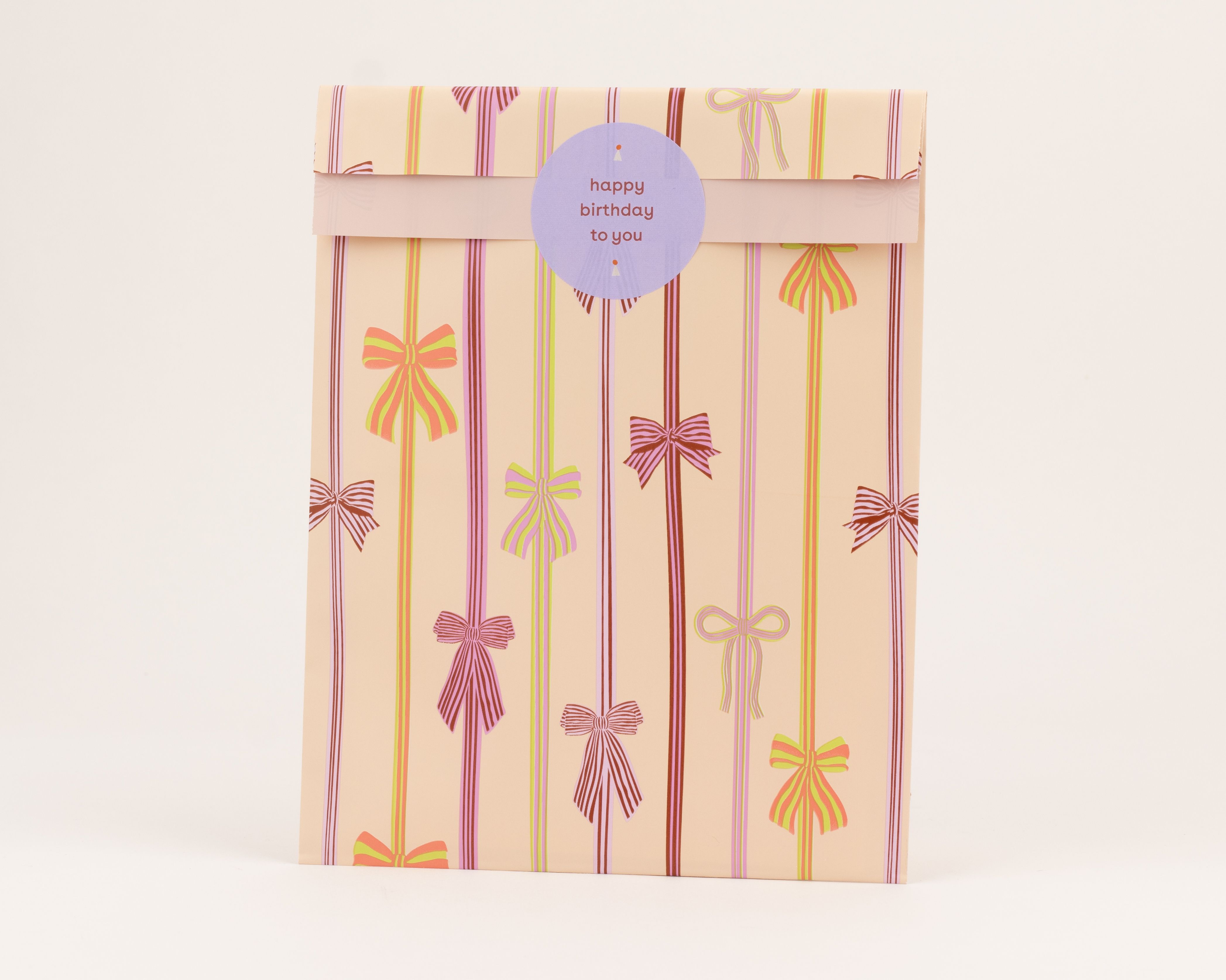 Flachbeutel mit Schleifenmuster in Pink, Grün, Hellviolett und Limettengrün auf aprikotfarbenem Grund, die Innenseite erscheint hellrosa