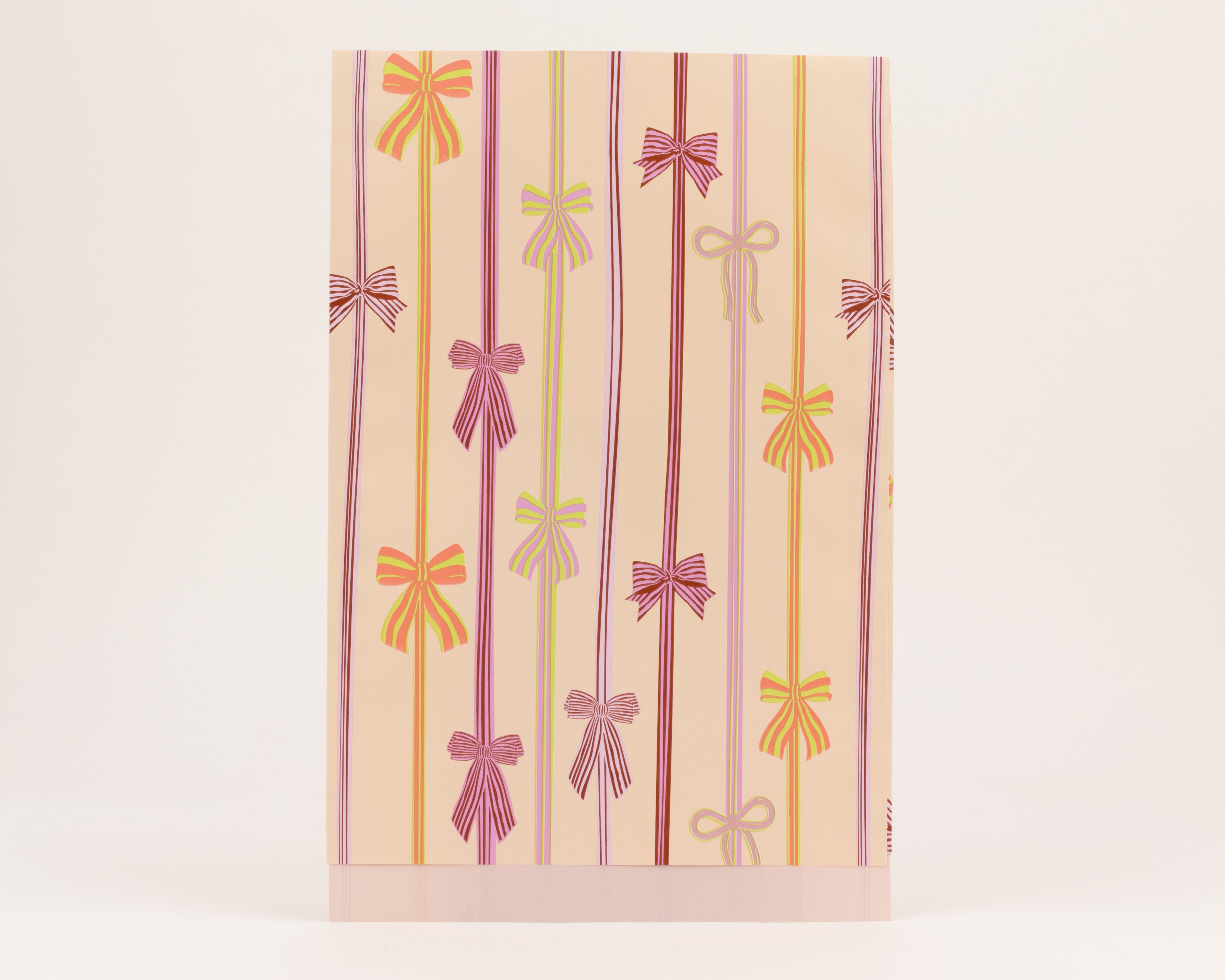 Flachbeutel mit aprikotfarbenem Hintergrund und einem Muster aus farbigen Schleifen und Streifen. Die Innenseite ist einfarbig Hellviolett