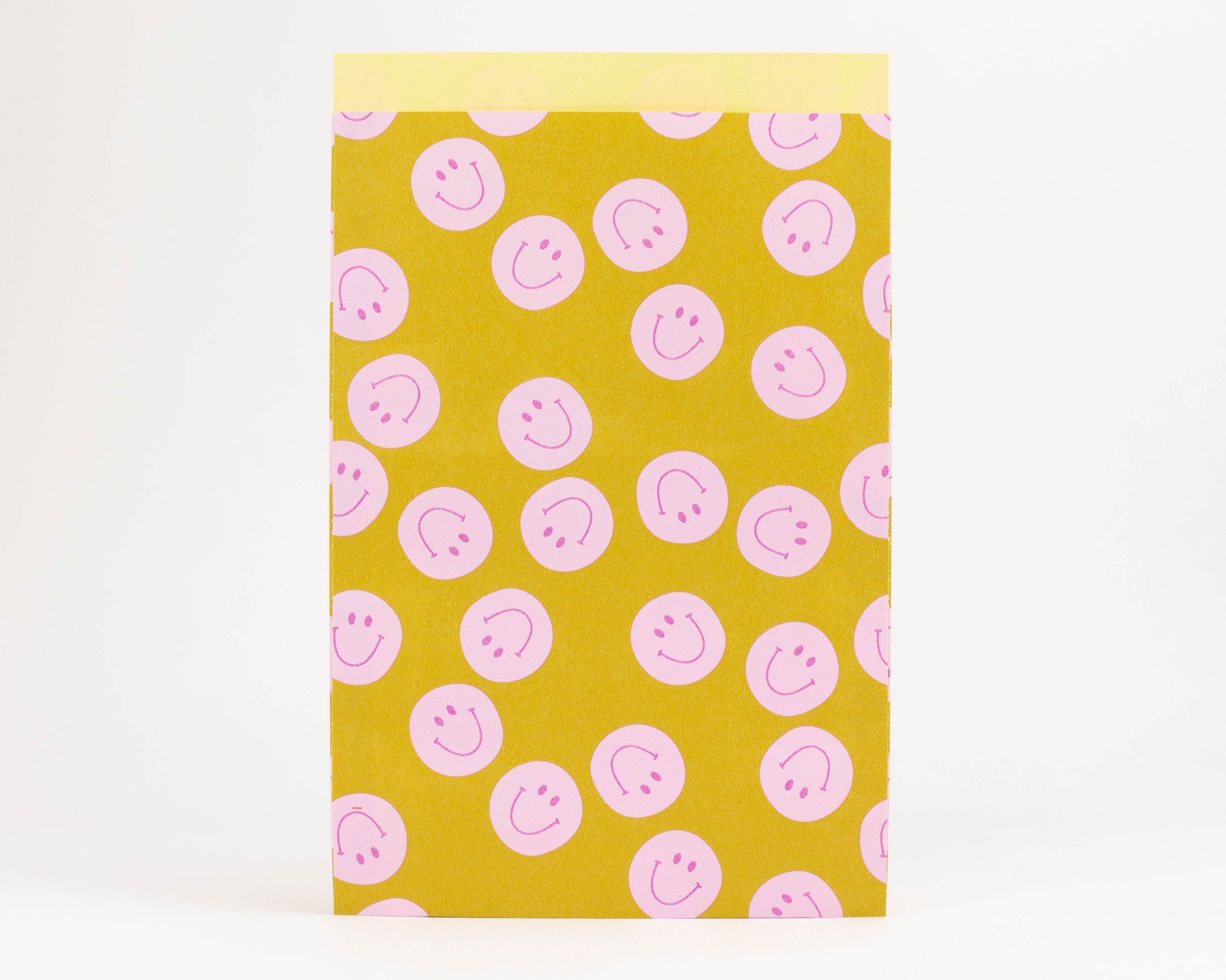 Flachbeutel mit einem Muster aus rosa Smileys auf gelbem Papier. Die Innenseite der Tüten zeigt eine helle gelbliche Färbung
