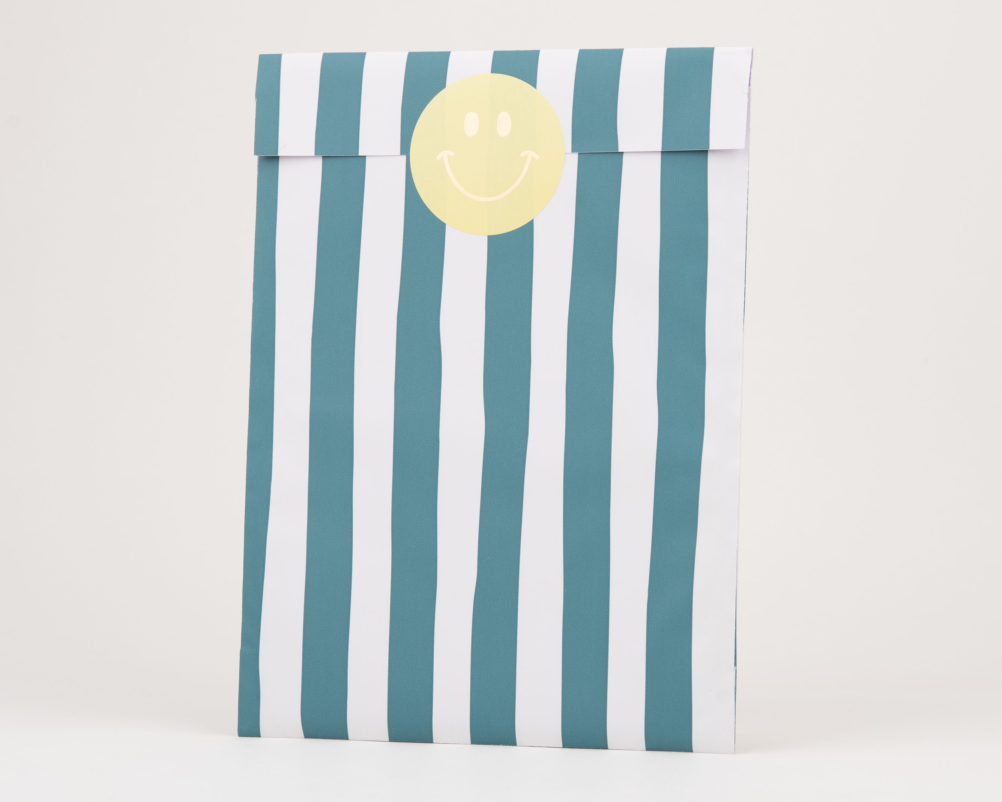 Papiertüten Flachbeutel mit einem markanten blau-weißen Streifenmuster auf der Außenseite, deren Innenseite weiß ist und die einen gelben Smiley-Aufkleber zeigen
