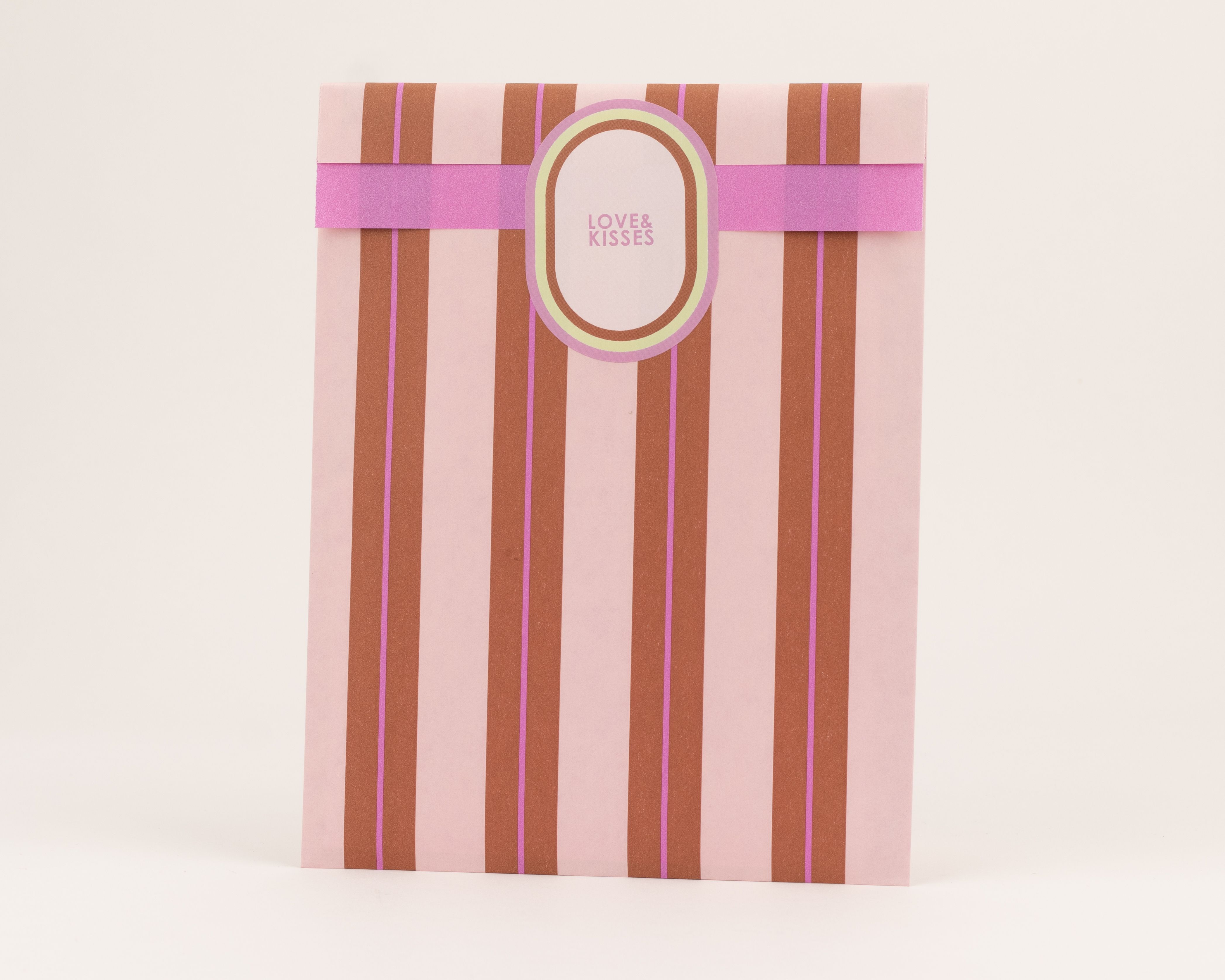 Flachbeutel mit vertikalen Streifen in Hellrosa, Braun und Pink. Eine lila Querbanderole und die hellrosa Innenseite sind sichtbar