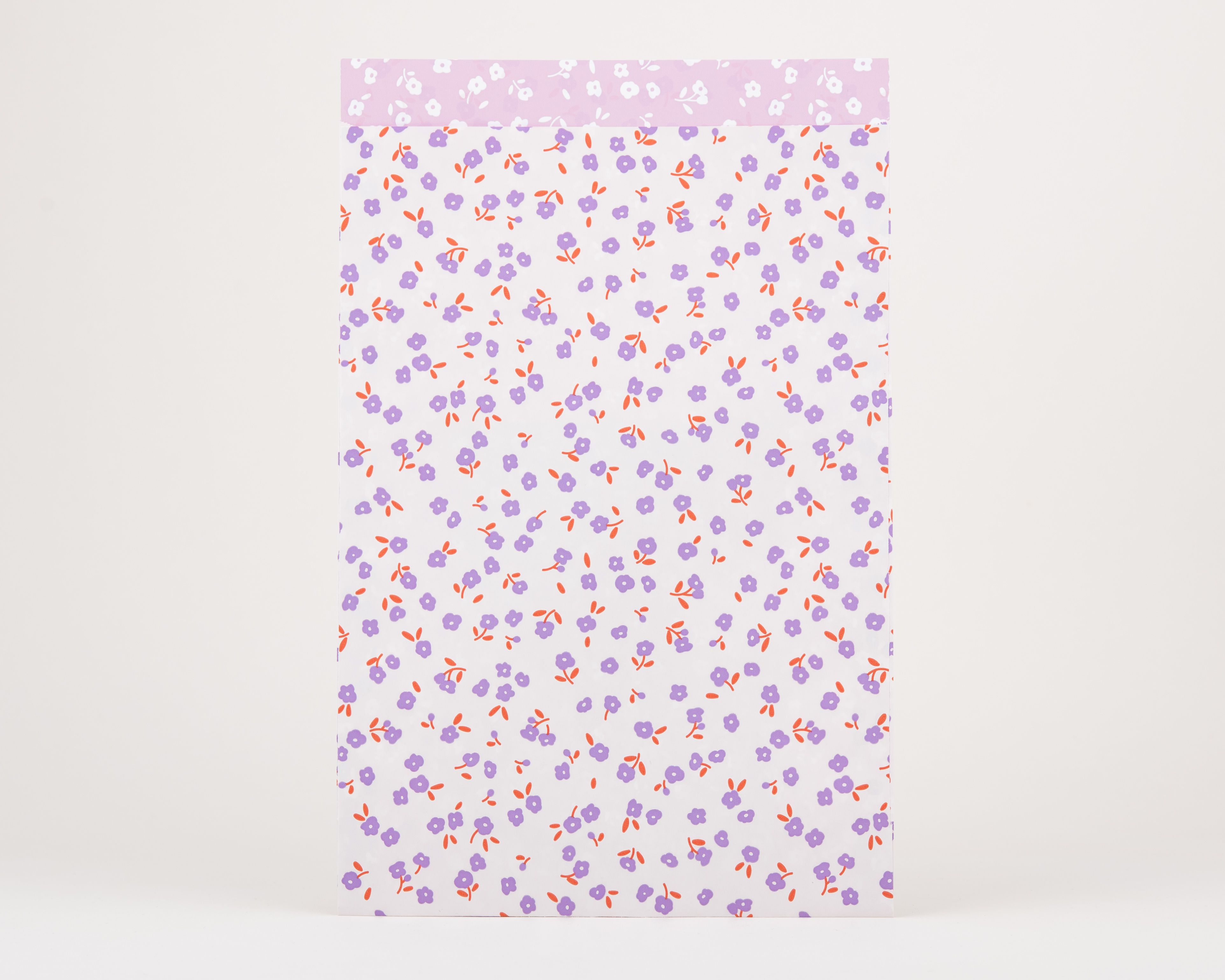 Papiertüten Flachbeutel mit fliederfarbenen Blüten und rostfarbenen Stielen auf weißer Außenseite. Innenseite ist hellfliederfarben mit weißen Blumen.