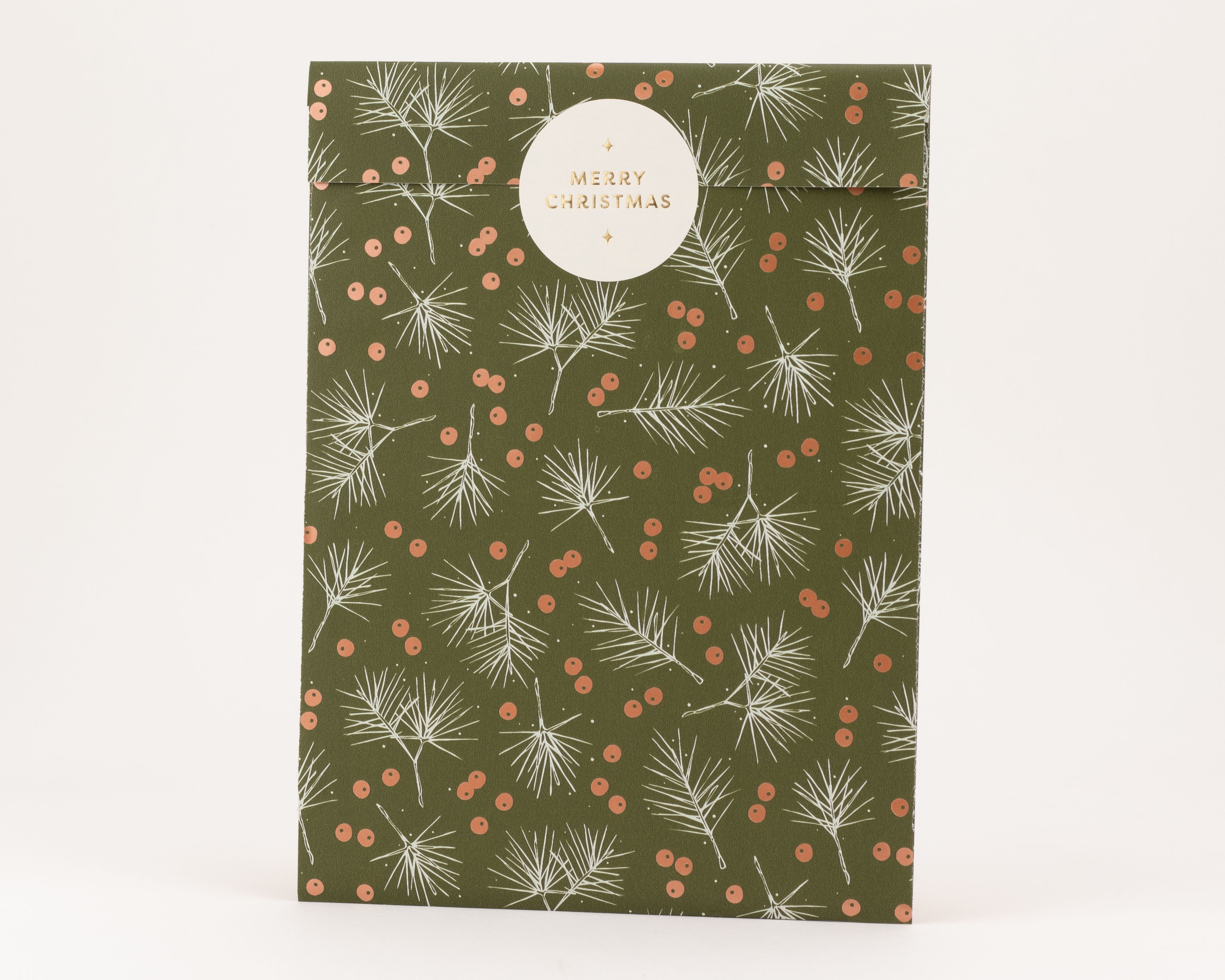 Papiertüten in Olivgrün mit weißen Tannenzweigen und glänzenden korallenrosa Beeren. Ein runder Aufkleber zeigt 'Merry Christmas' in Gold.