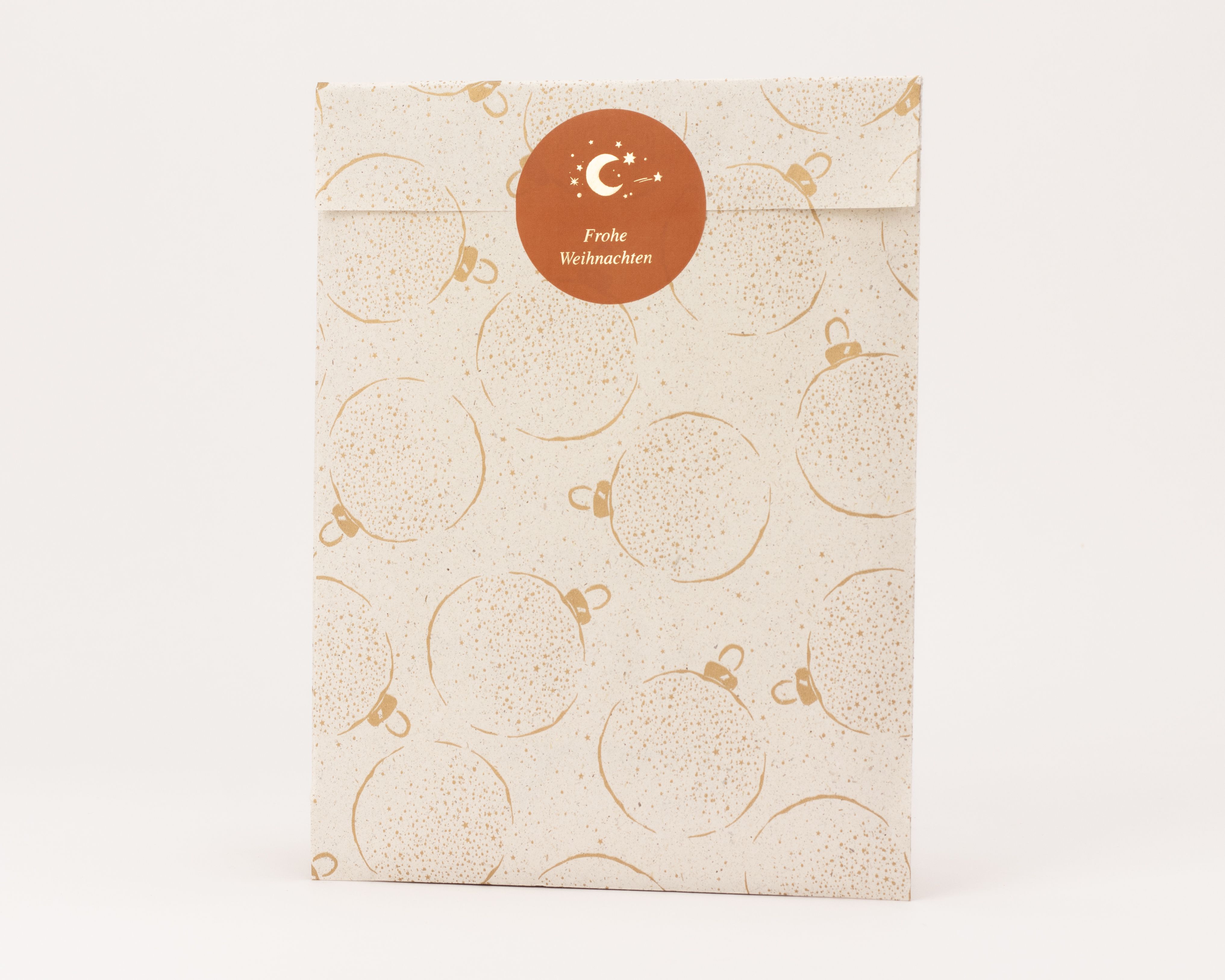 Flachbeutel aus Kraftpapier mit durchgängigem goldenem Weihnachtskugel-Muster und Sternen, ein runder Frohe Weihnachten Aufkleber verschließt die Tüte