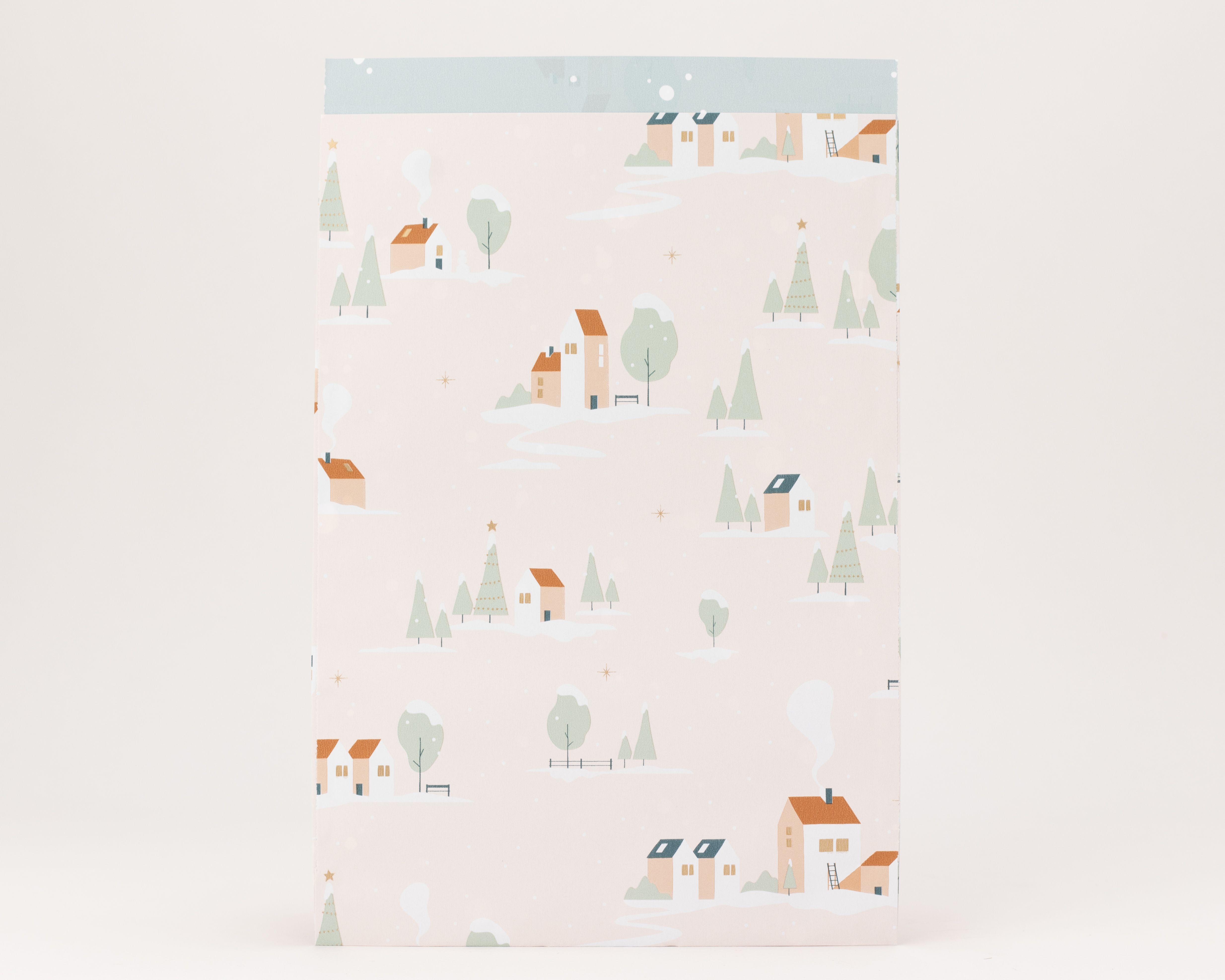 Flachbeutel in Rosa mit Winterdorf-Motiv, Haeusern, Baeumen und Schnee. Goldene Sterne und Punkte zieren das Design, Innenseite hellblau