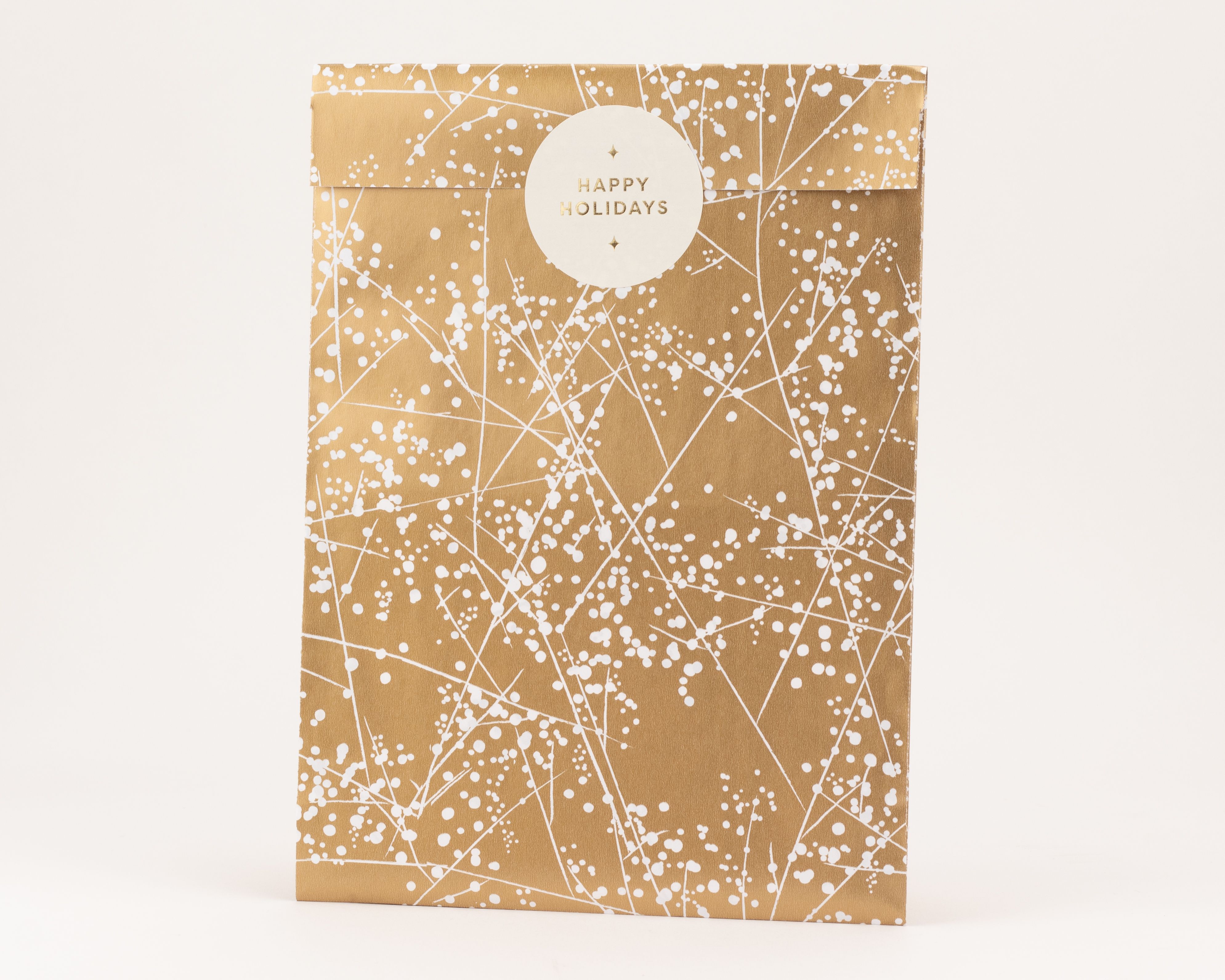 Flachbeutel in Gold mit weißem Winterfrost-Muster und einem runden weißen Aufkleber. Die Innenseite ist schlicht weiß