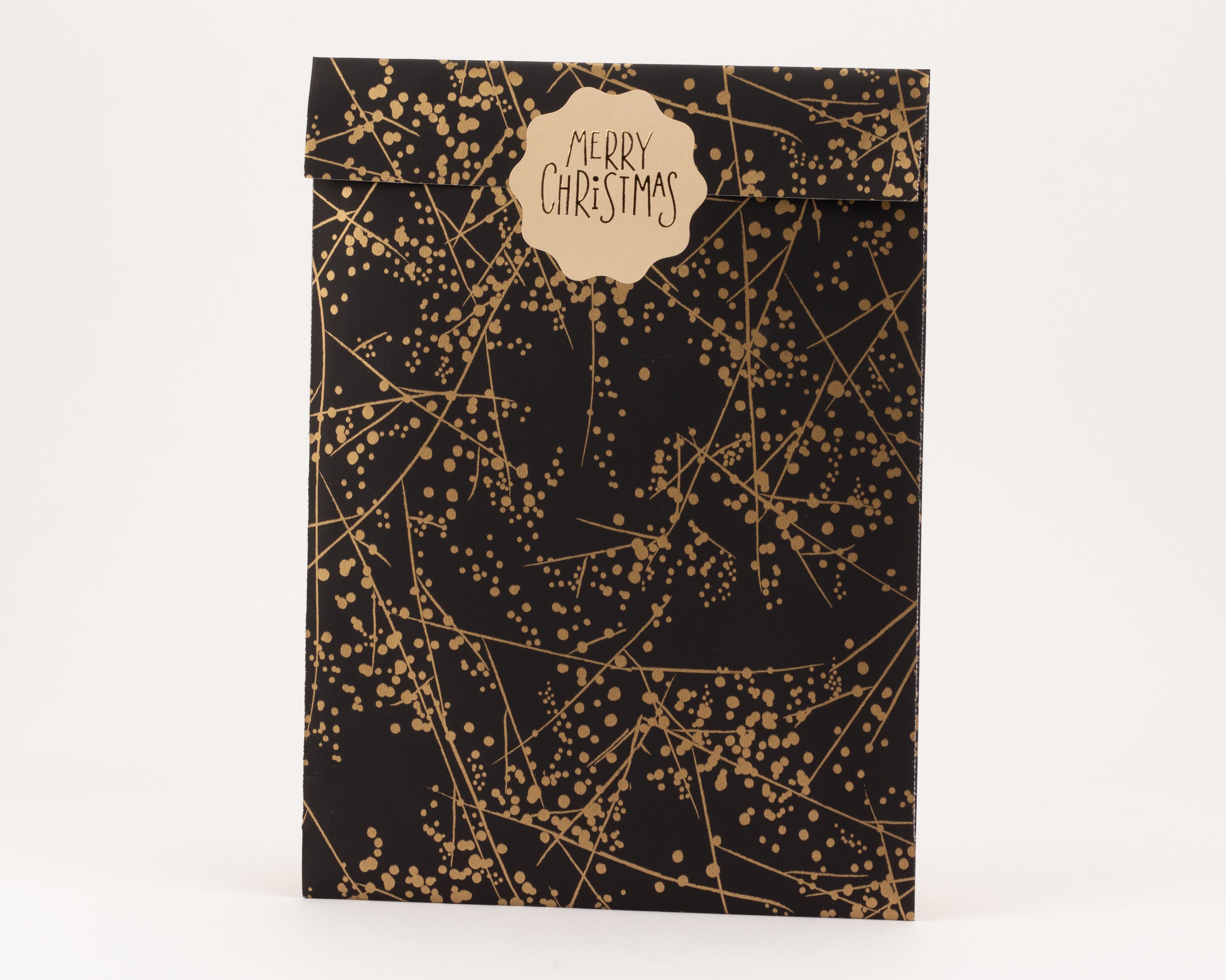Flachbeutel mit Winterfrost-Muster in Schwarz und Gold, verziert mit einem beigefarbenen Anhänger mit der Aufschrift 'Merry Christmas'