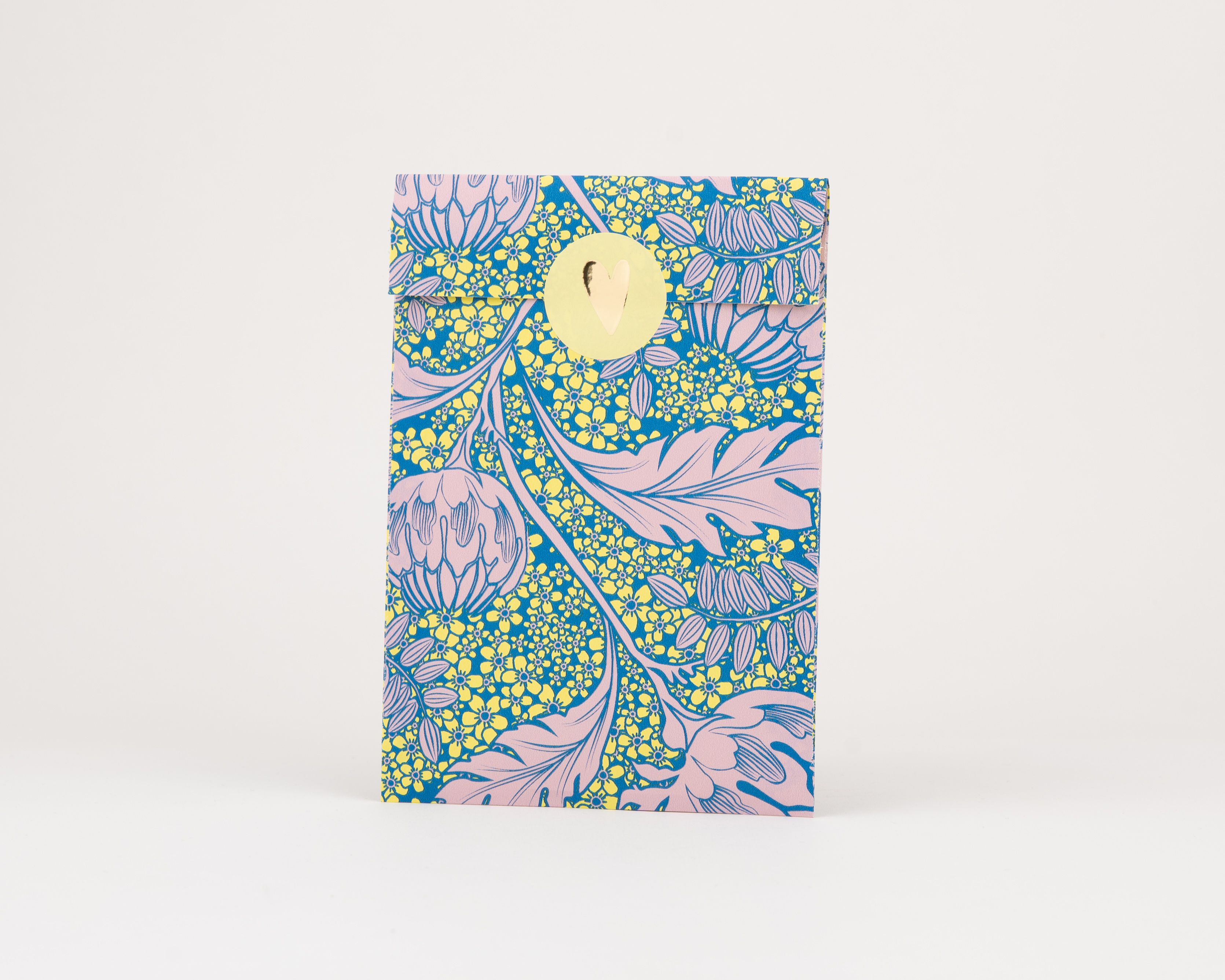 Papiertüten Flachbeutel zeigen ein lebhaftes Artischockenmuster in Rosa auf blauem Hintergrund mit gelben Blüten. Die Innenseite der Tüten ist Rosa.