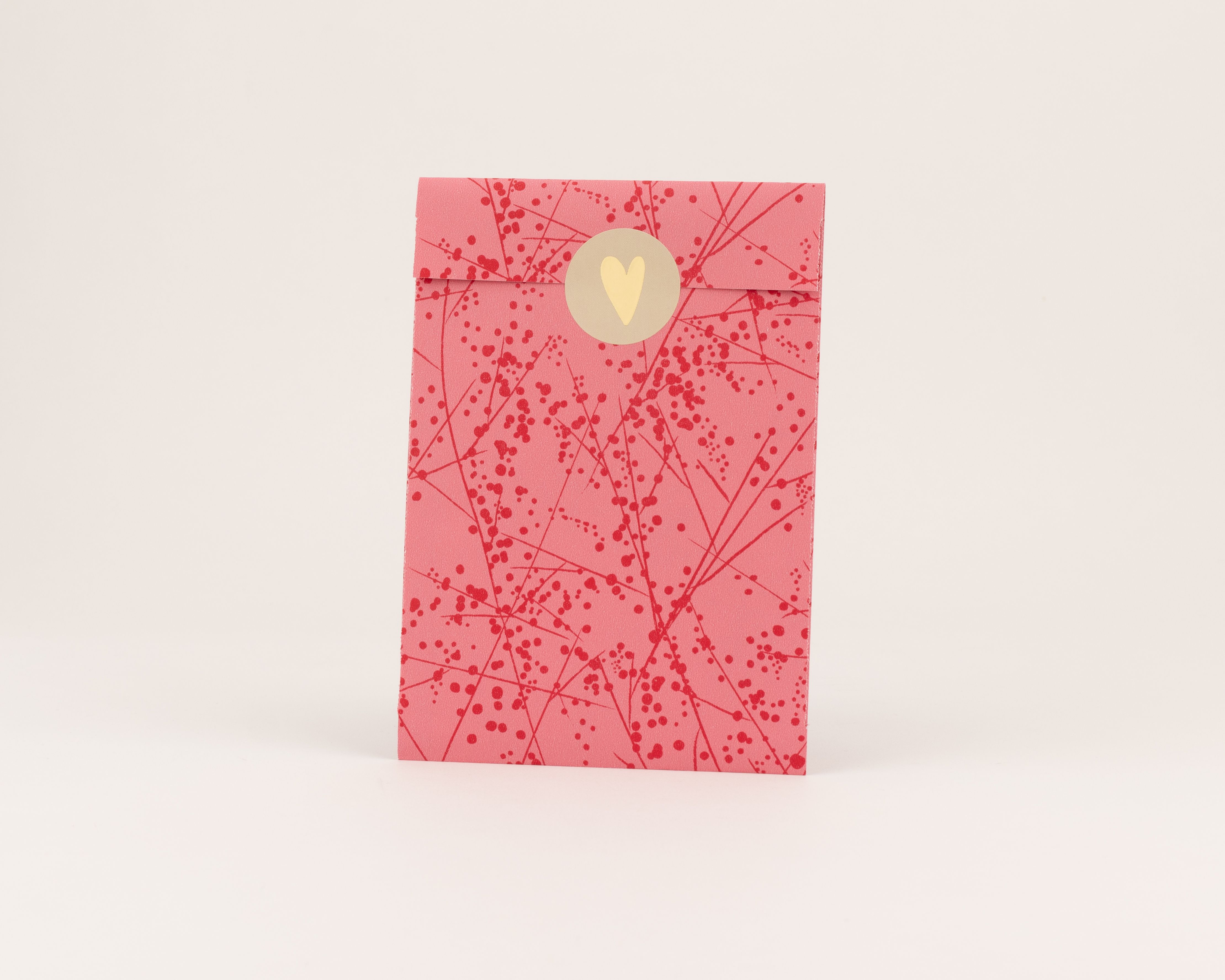 Papiertüten in Pink mit rotem Linien- und Punktemuster. Ein goldener Herz-Aufkleber verschließt die Tüte. Die Innenseite ist Pink und gemustert