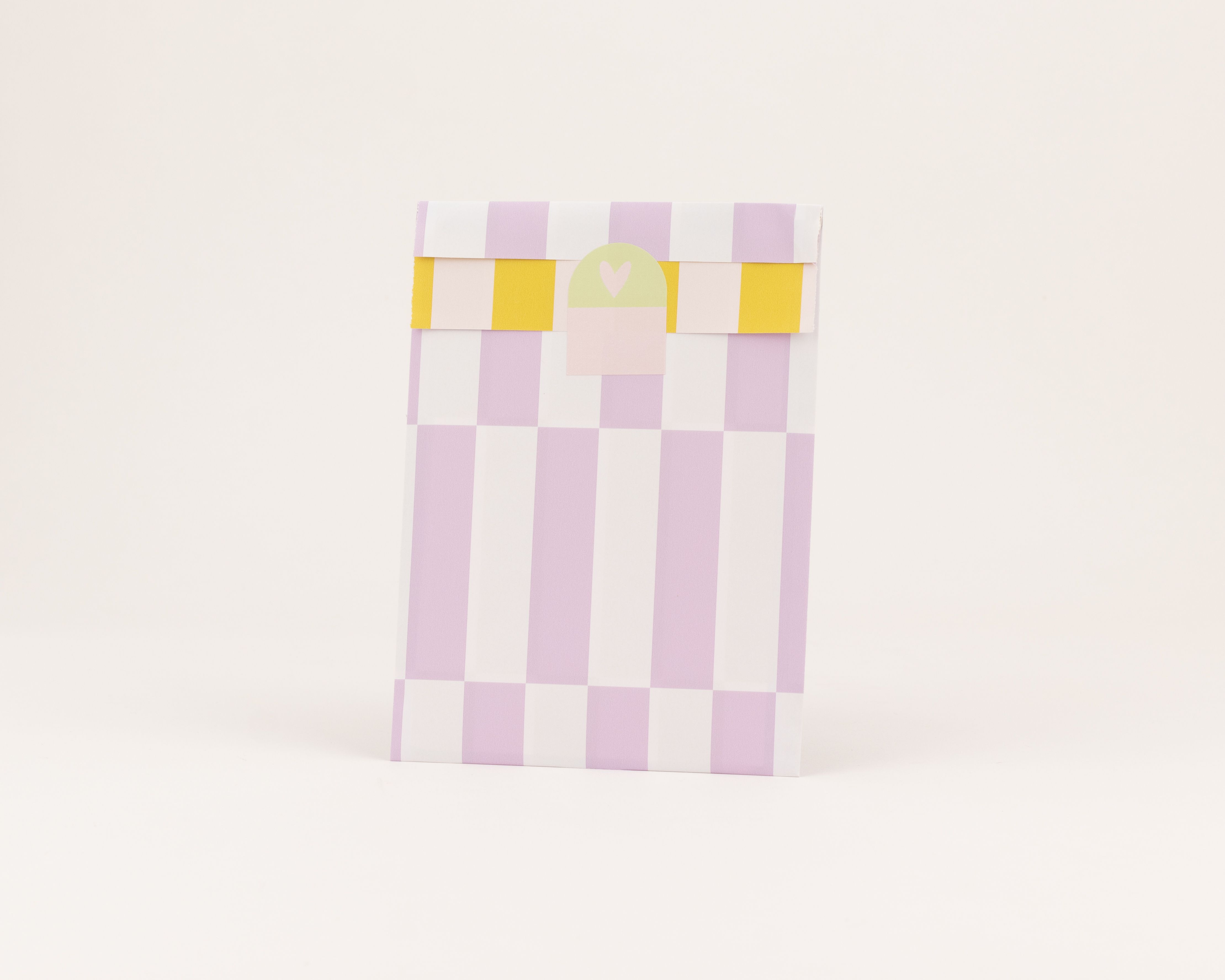 Flachbeutel mit Flieder- und Weiß-gestreiften Muster, die gelbe Innenseite ist mit einem kleinen hellgrünen Herzaufkleber versehen