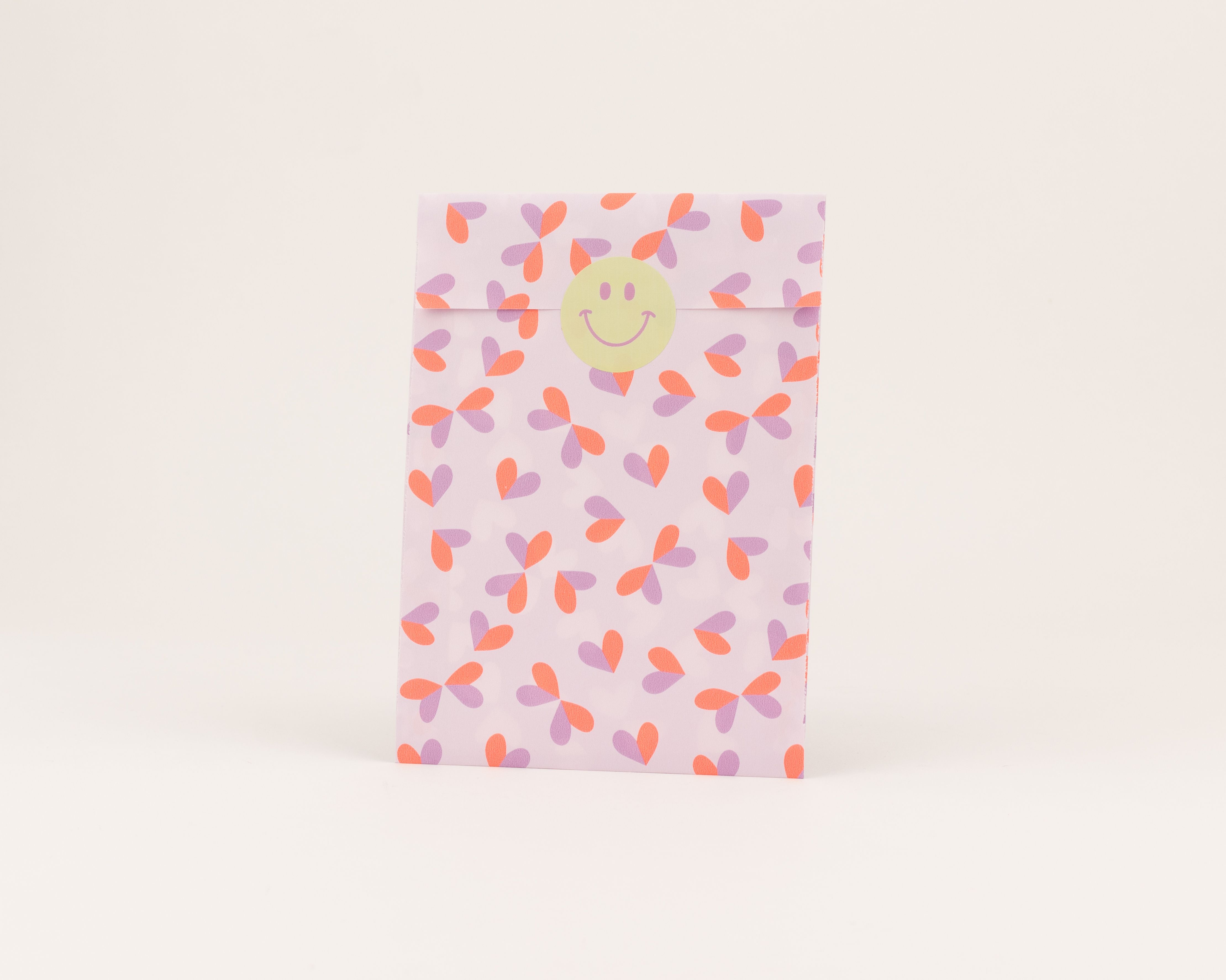 Flachbeutel in Hellflieder mit einem Muster aus stilisierten Herzformen in Hellflieder und Neon Orange, die Innenseite ist ebenfalls Hellflieder