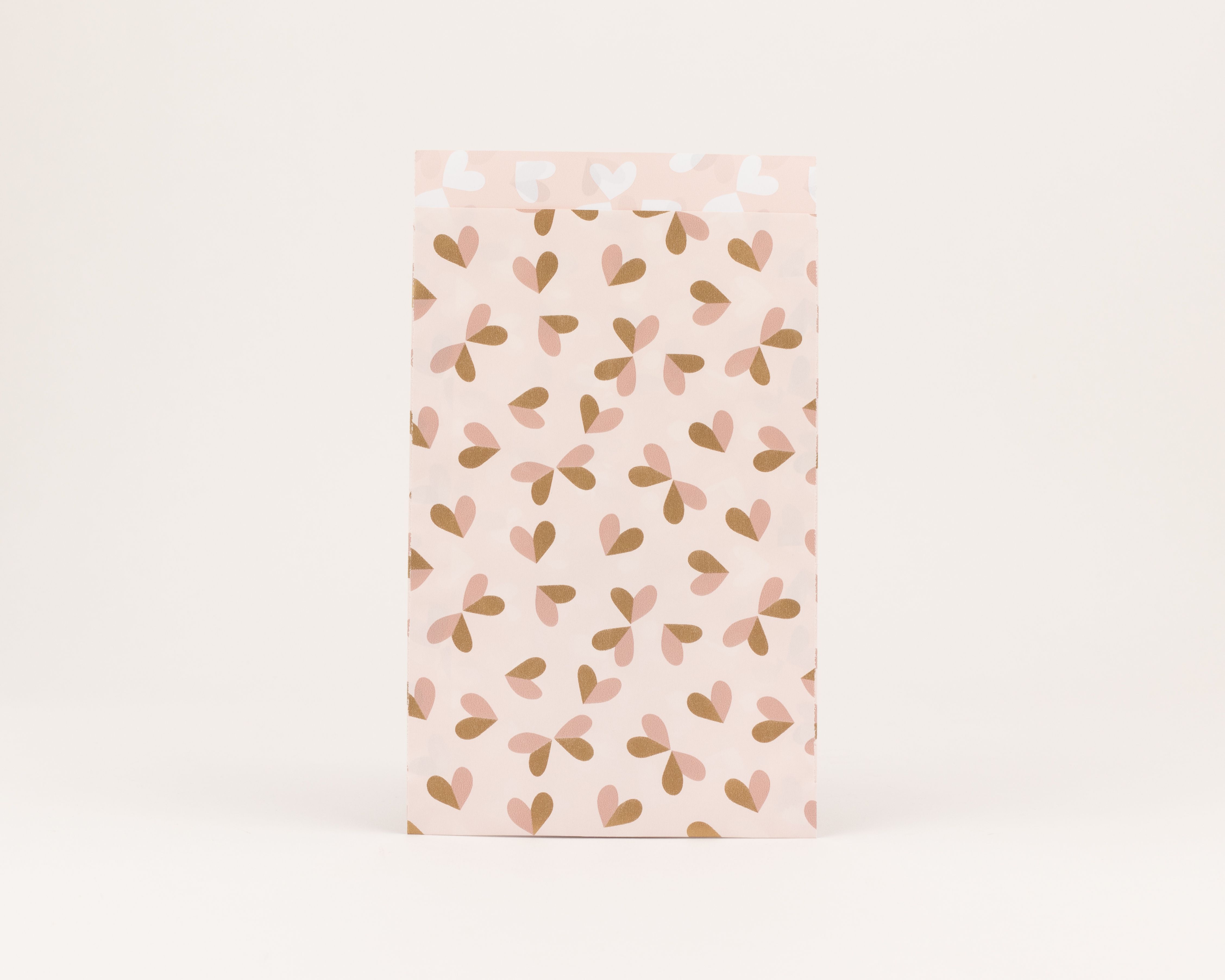 Flachbeutel mit einem Muster aus hellrosa und rostbraunen Herzen auf hellrosa Hintergrund. Die Innenseite zeigt Herzen in Hellrosa und Beige