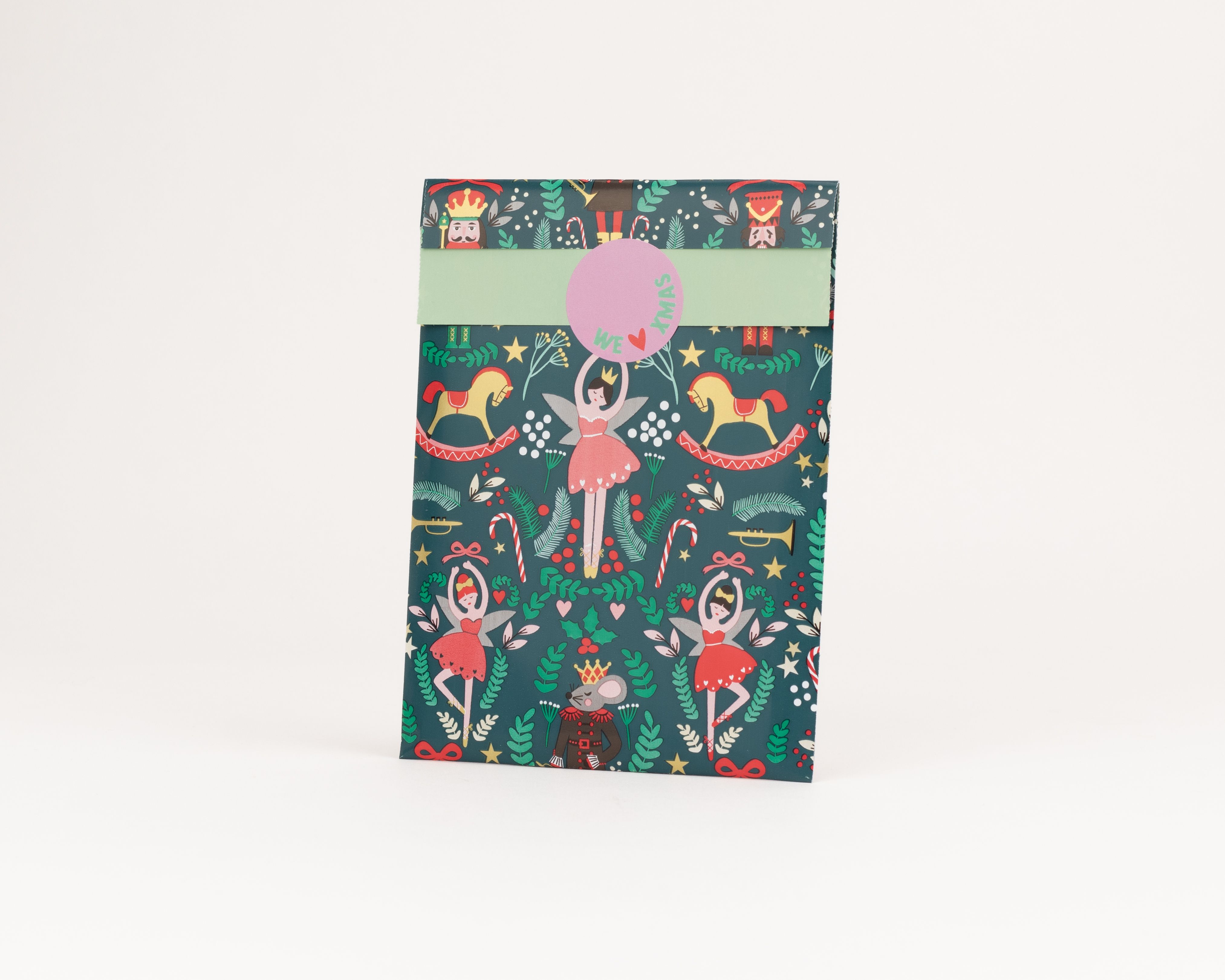 Flachbeutel mit dunkelgrünem Hintergrund und weihnachtlichem Nussknacker Motiv mit Ballerinas und Schaukelpferden, die Innenseite ist hellgrün