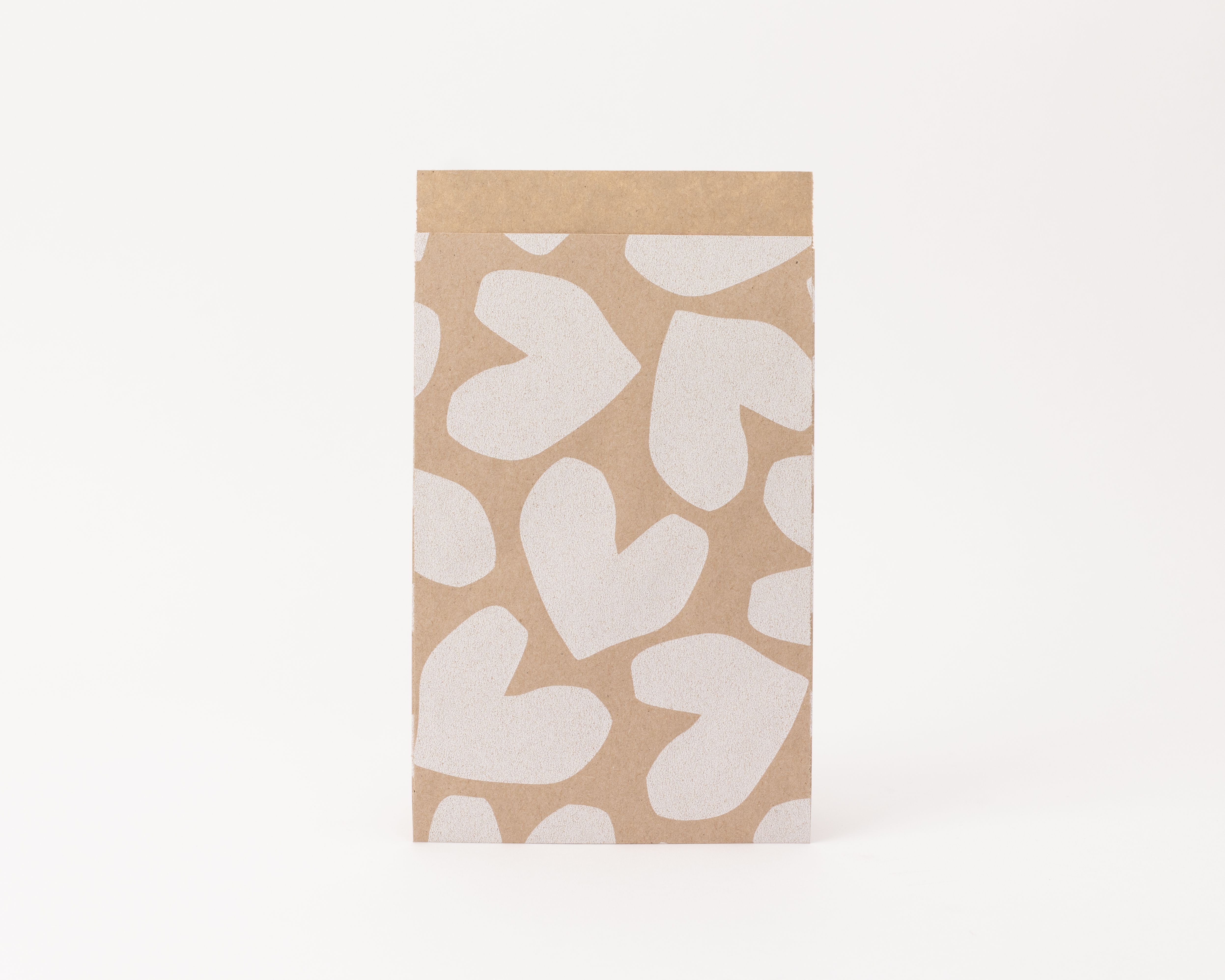 Flachbeutel mit Kraftpapier-Außenseite und weißen Herzmustern, die Innenseite ist schlicht Kraft