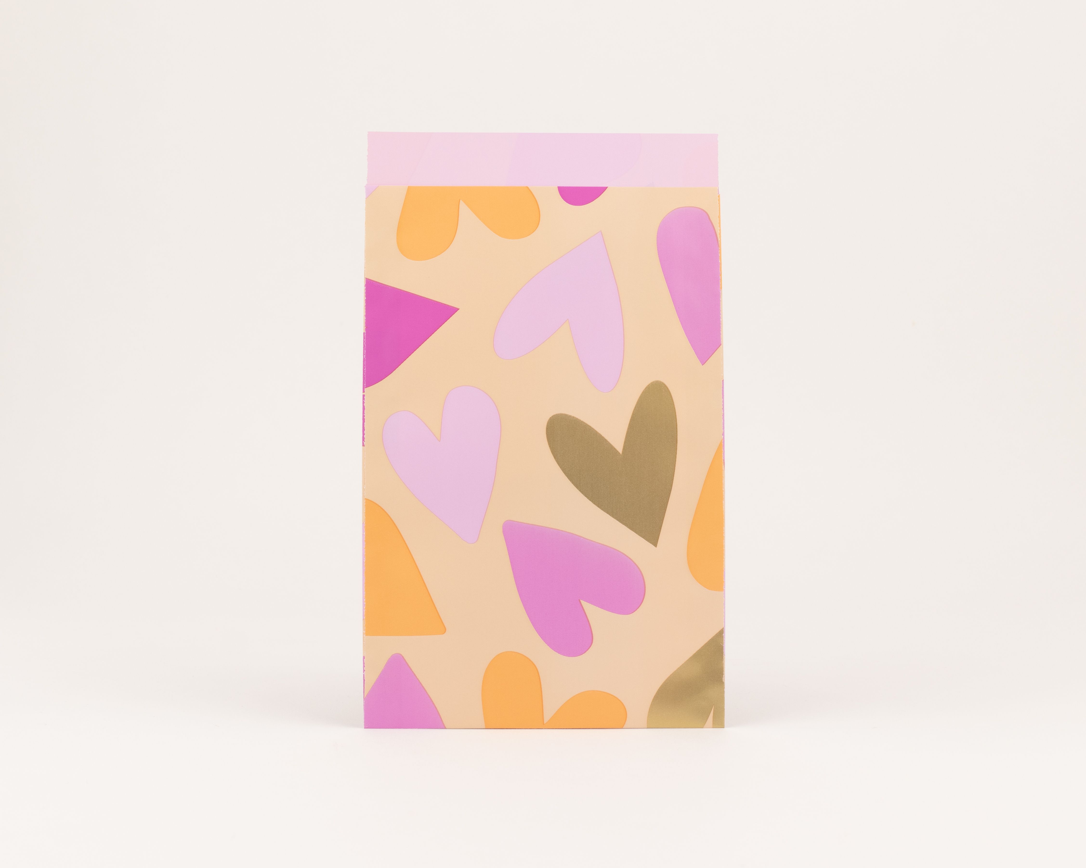 Flachbeutel mit einem bunten Muster aus Herzen und Formen in Orange, Pink und Gold auf pfirsichfarbenem Hintergrund, die Innenseite ist Hellpink