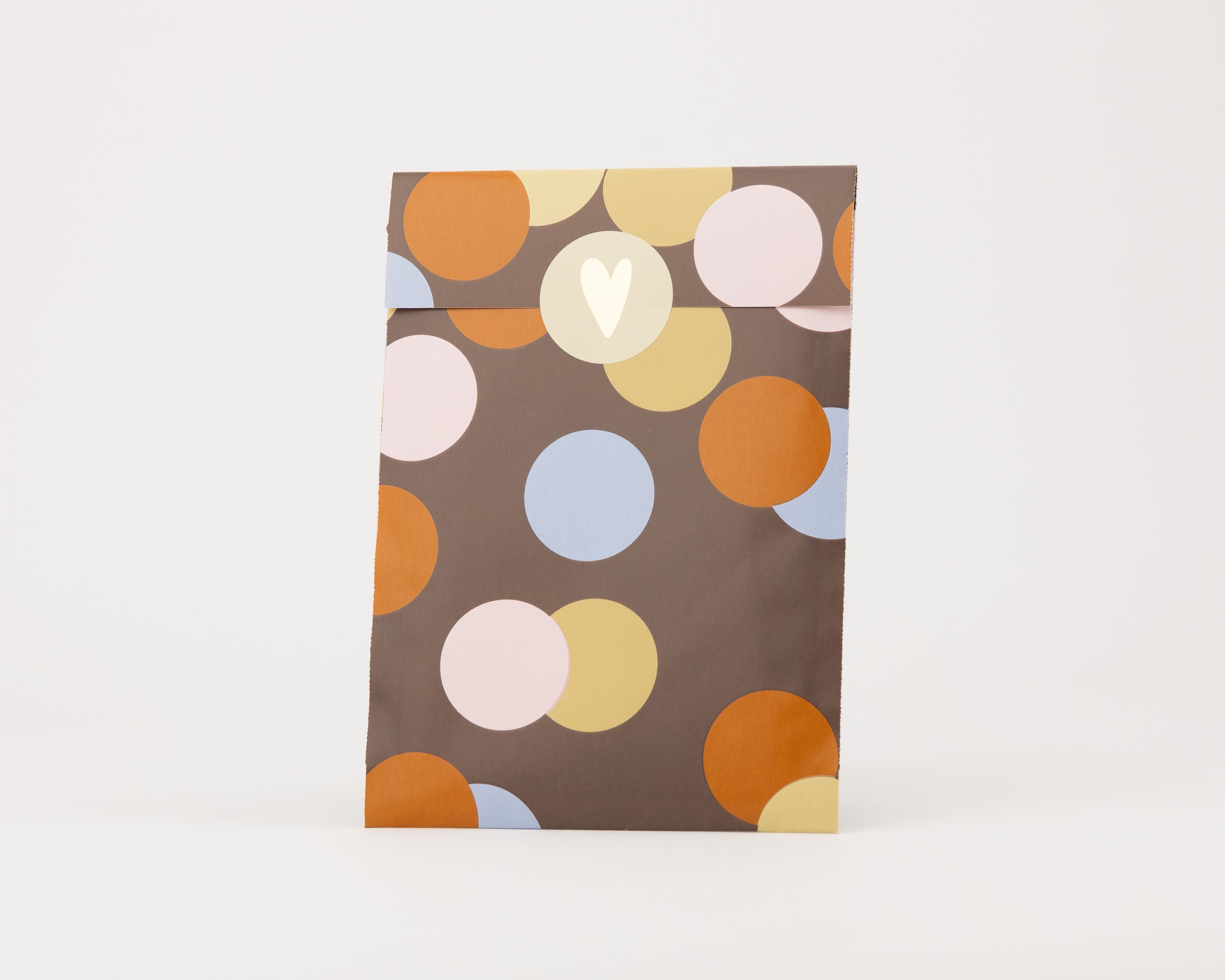 Papiertüten Flachbeutel mit braunem Hintergrund und einem Konfettimuster aus Kreisen in Gold, Hellblau, Orange und Beige, verziert mit einem hellen Herzmotiv