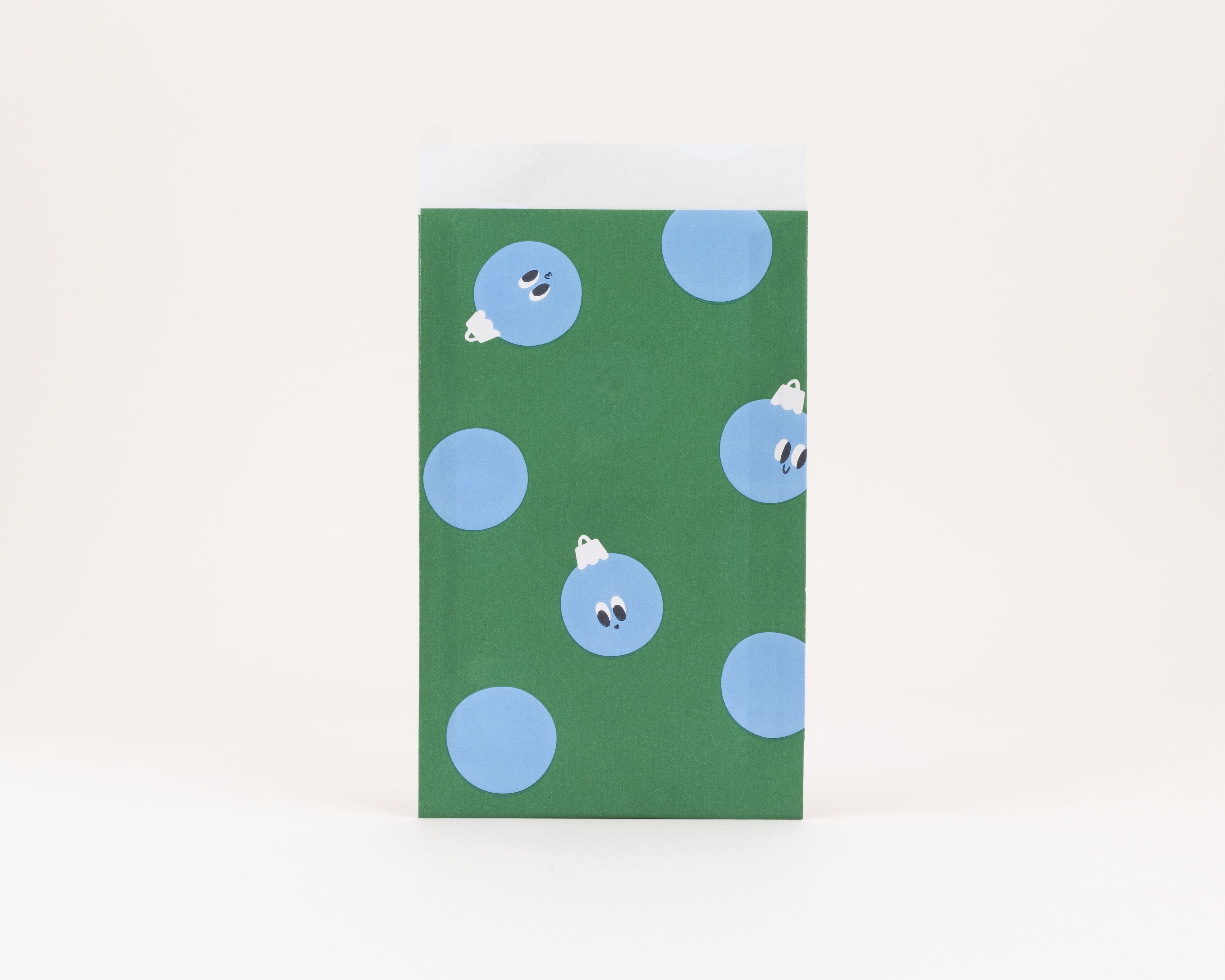 Flachbeutel in Grün mit blauen, teilweise mit Gesichtern versehenen Kugelmotiven Die Innenseite ist weiß