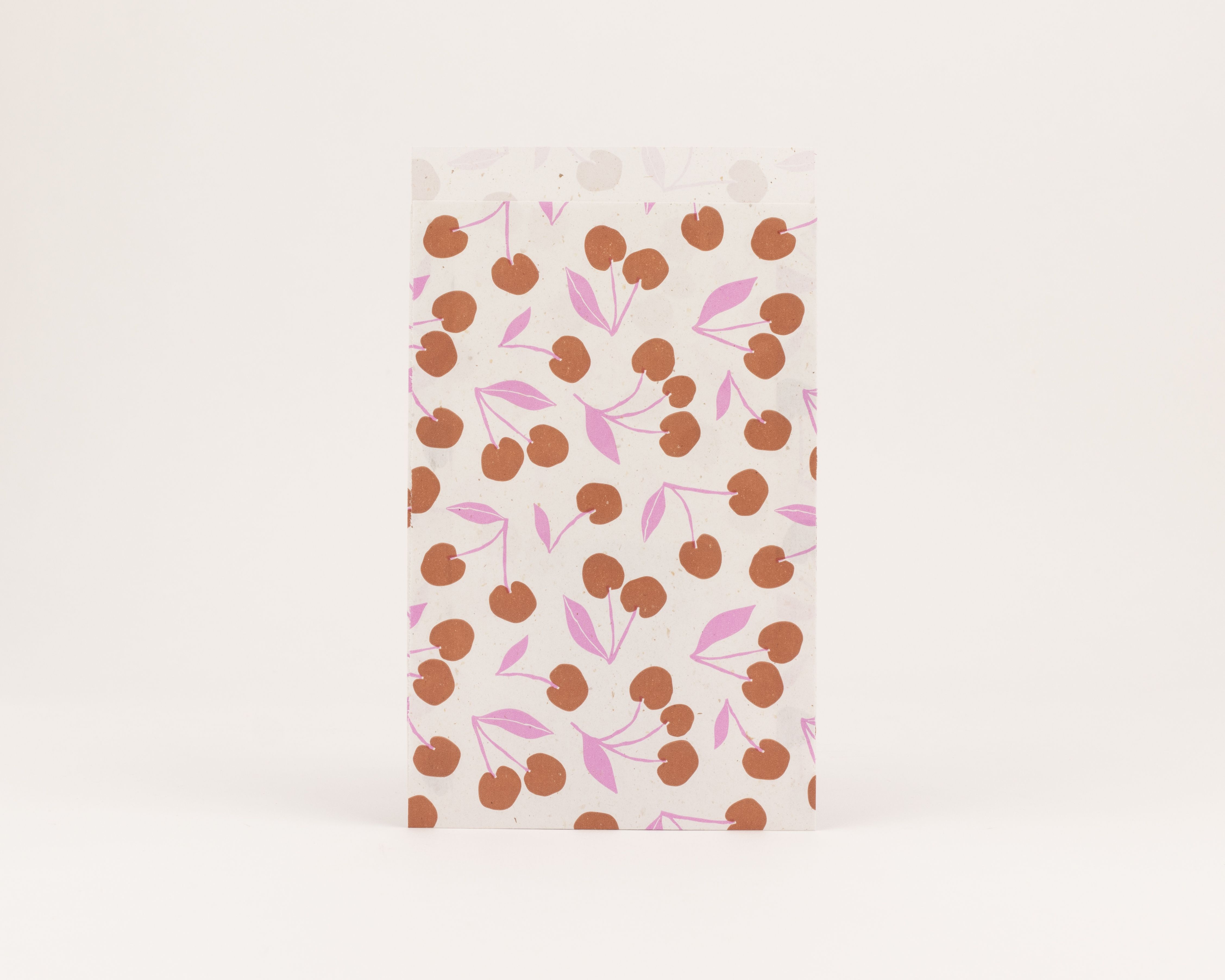 Flachbeutel mit einem Retro Kirschmuster in Braun und Pink auf hellem, gesprenkeltem Papier Die Innenseite ist ebenfalls hell und gesprenkelt
