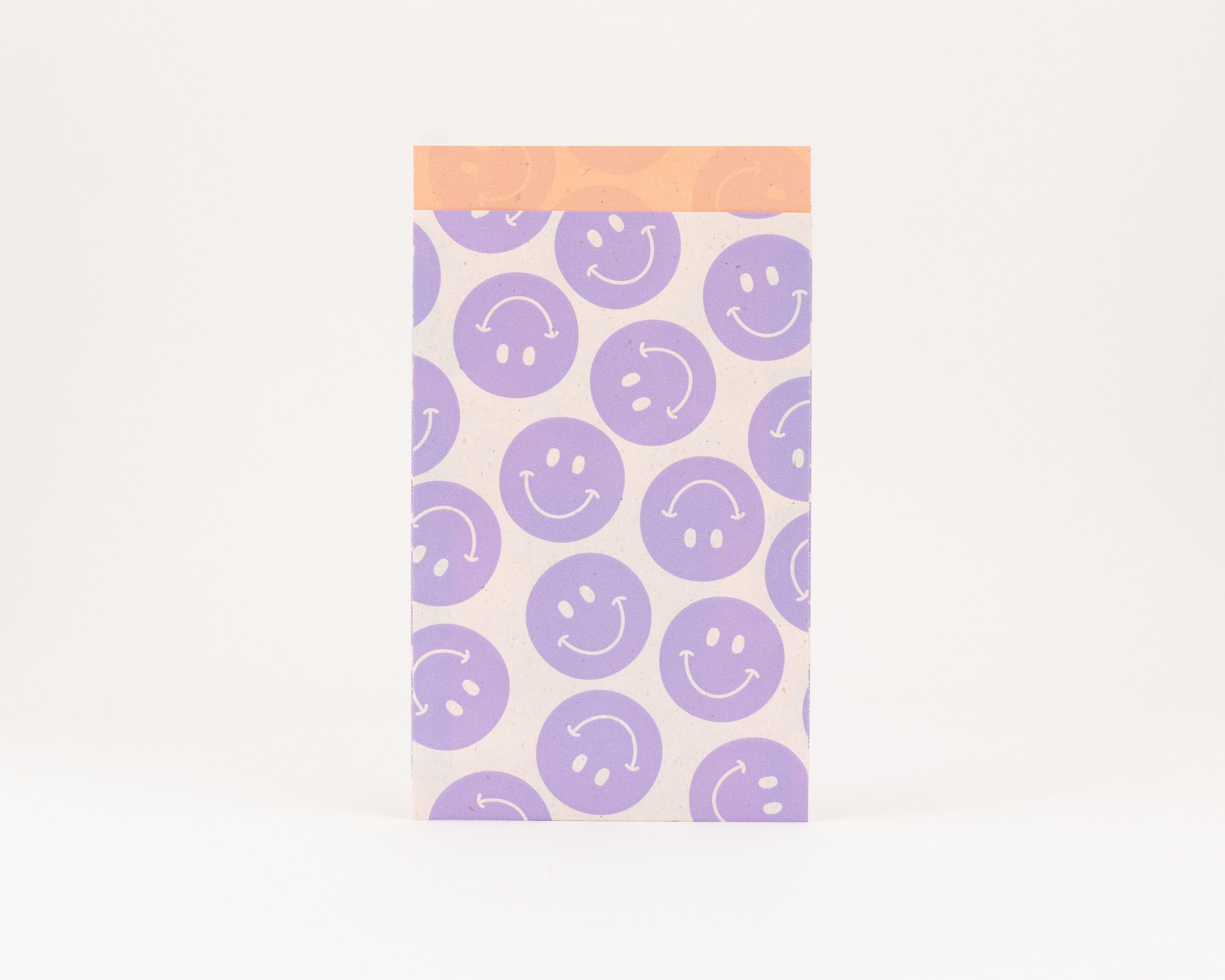 Flachbeutel mit einem Muster aus fliederfarbenen Smileys auf der Außenseite und einer orangefarbenen Innenseite
