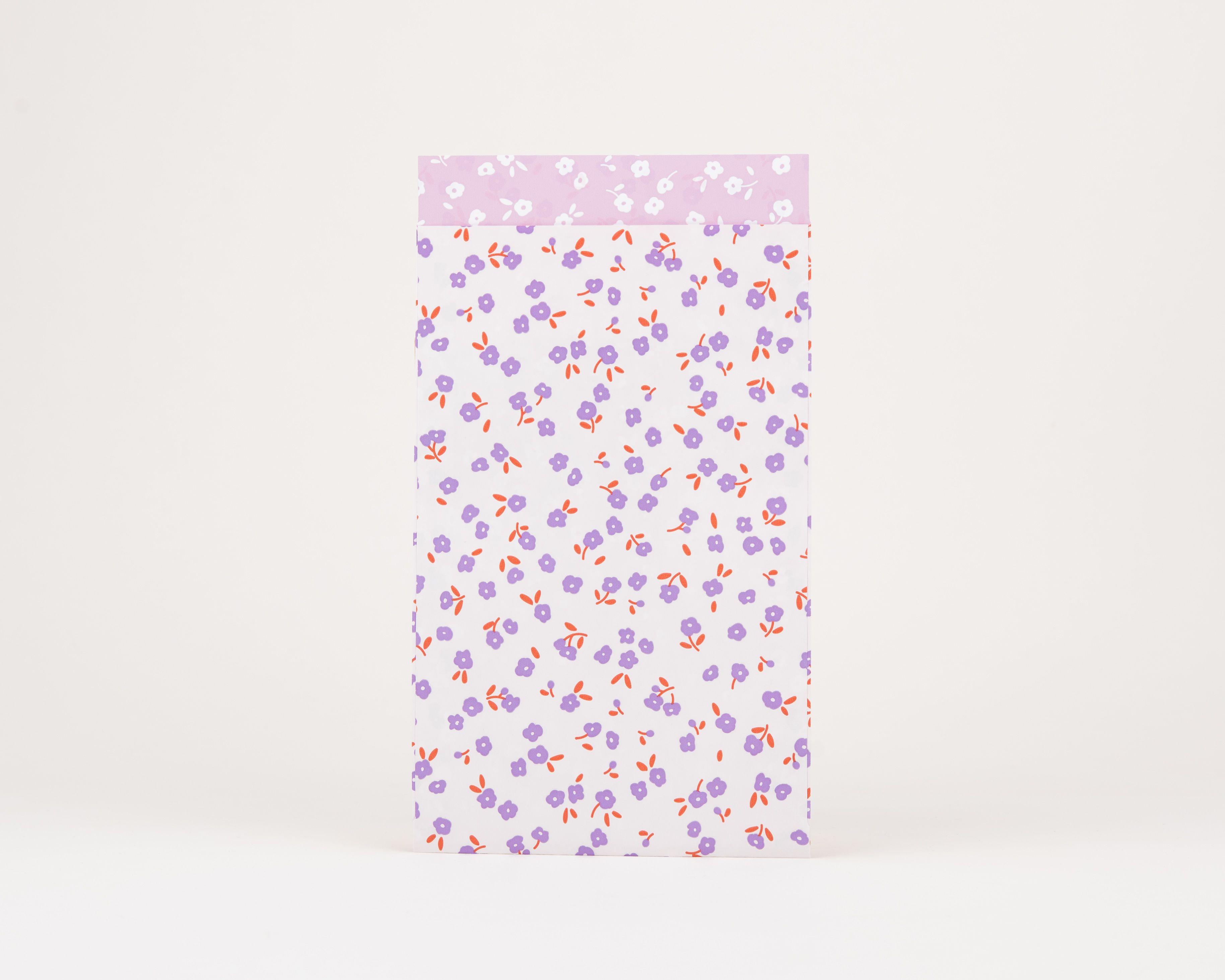 Papiertüten Flachbeutel mit einem Blumenmuster in Flieder und Rost auf weißem Hintergrund. Die Innenseite zeigt weiße Blumen auf hellfliederfarbenem Hintergrund.