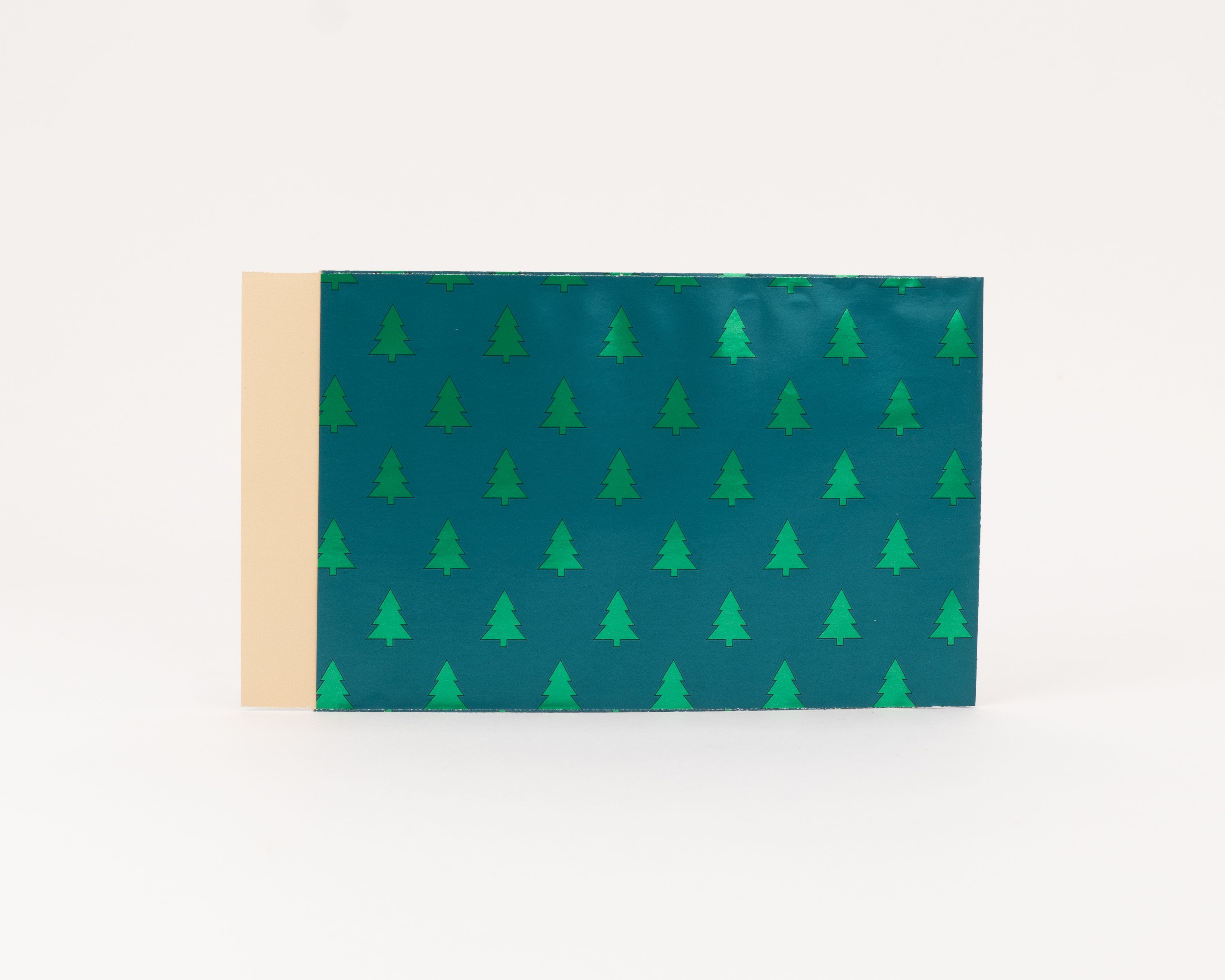 Flachbeutel mit einem grünen Grundton und einem Muster aus metallisch glänzenden Tannenbäumen die Innenseite ist beige