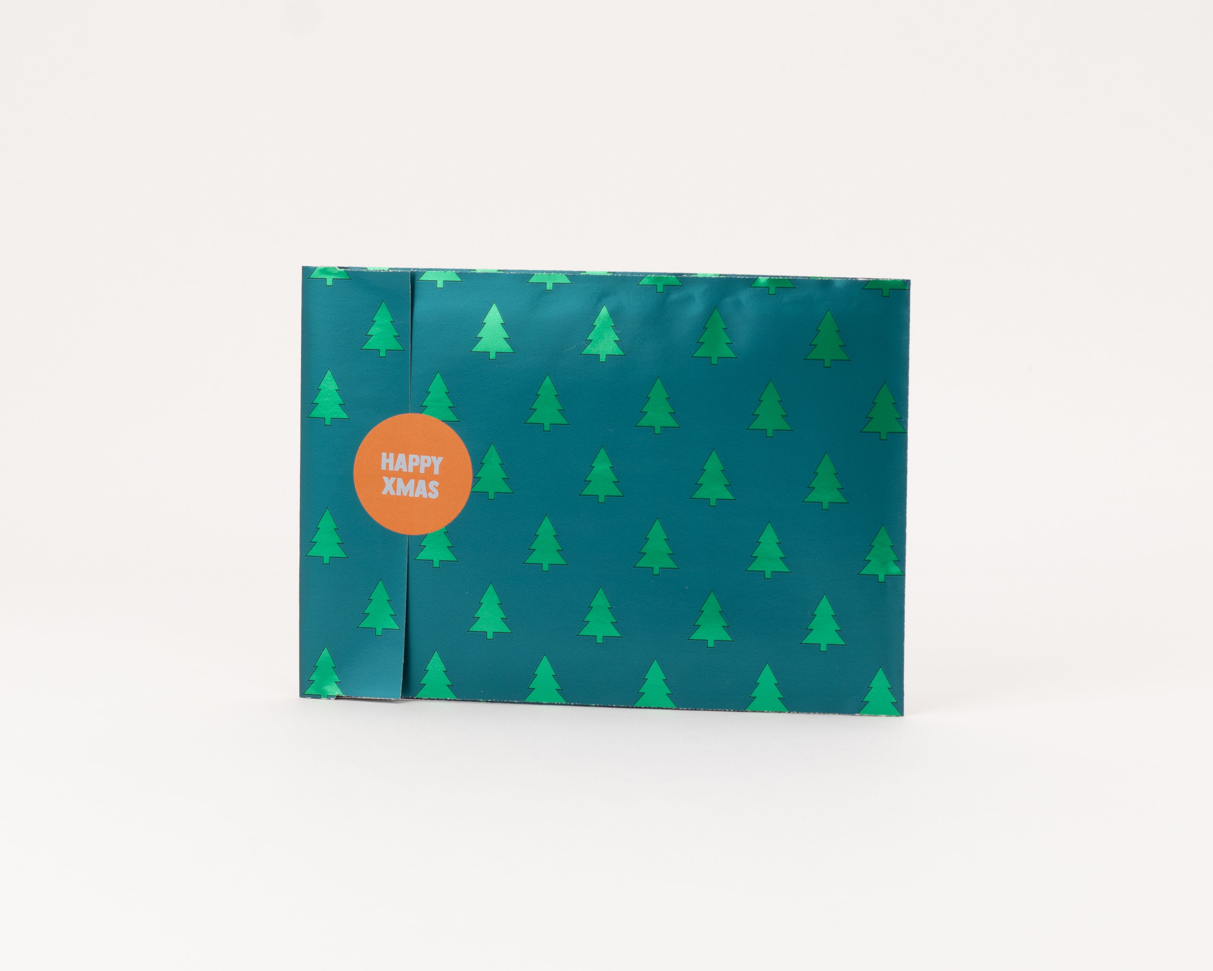 Flachbeutel mit einem grünen Außenmuster von metallisch glänzenden Tannen und einer beigen Innenseite