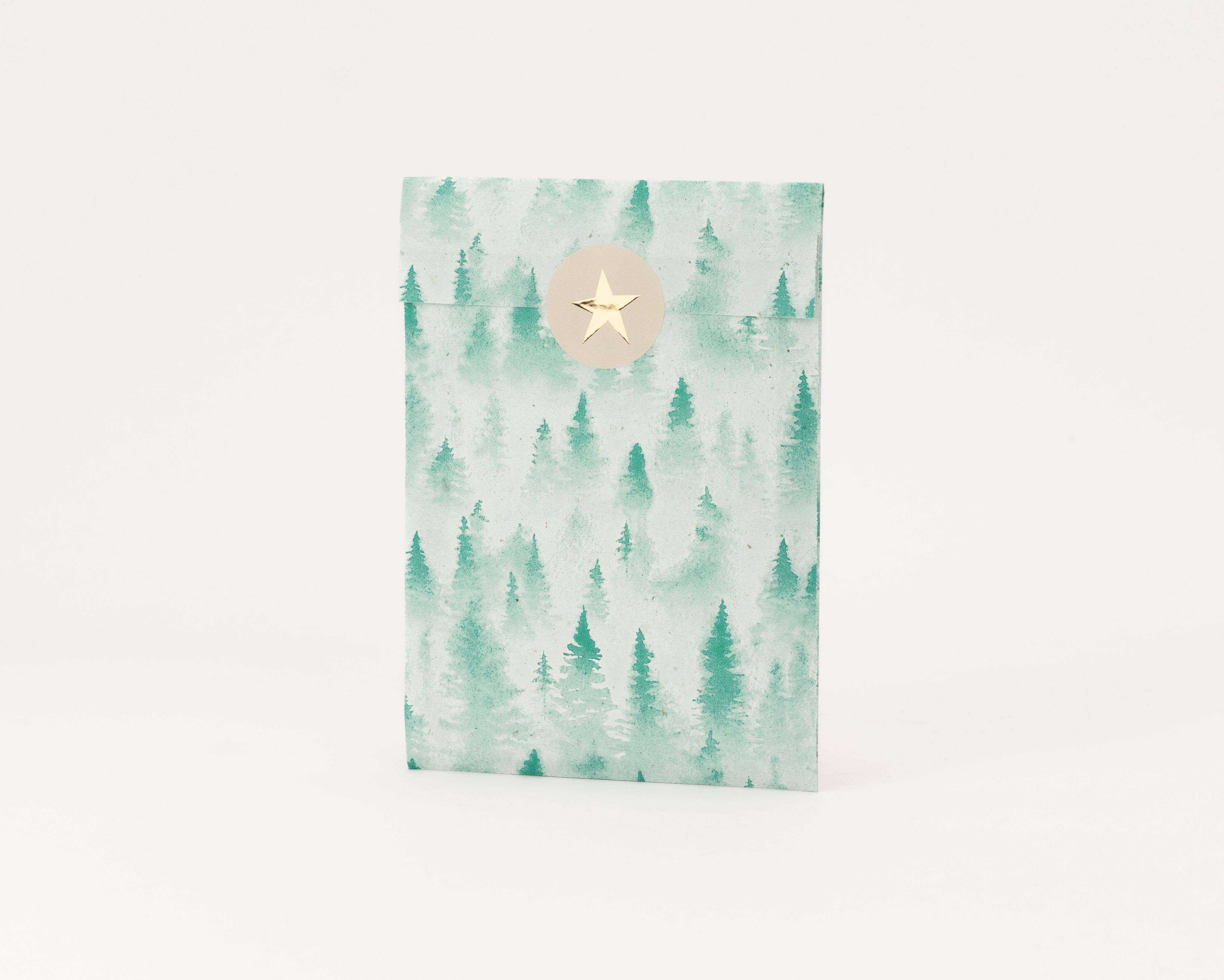 Flachbeutel mit einem grünen Tannenwaldmuster auf der Außenseite und einem beigefarbenen Aufkleber mit goldenem Stern Die Innenseite ist hellbeige