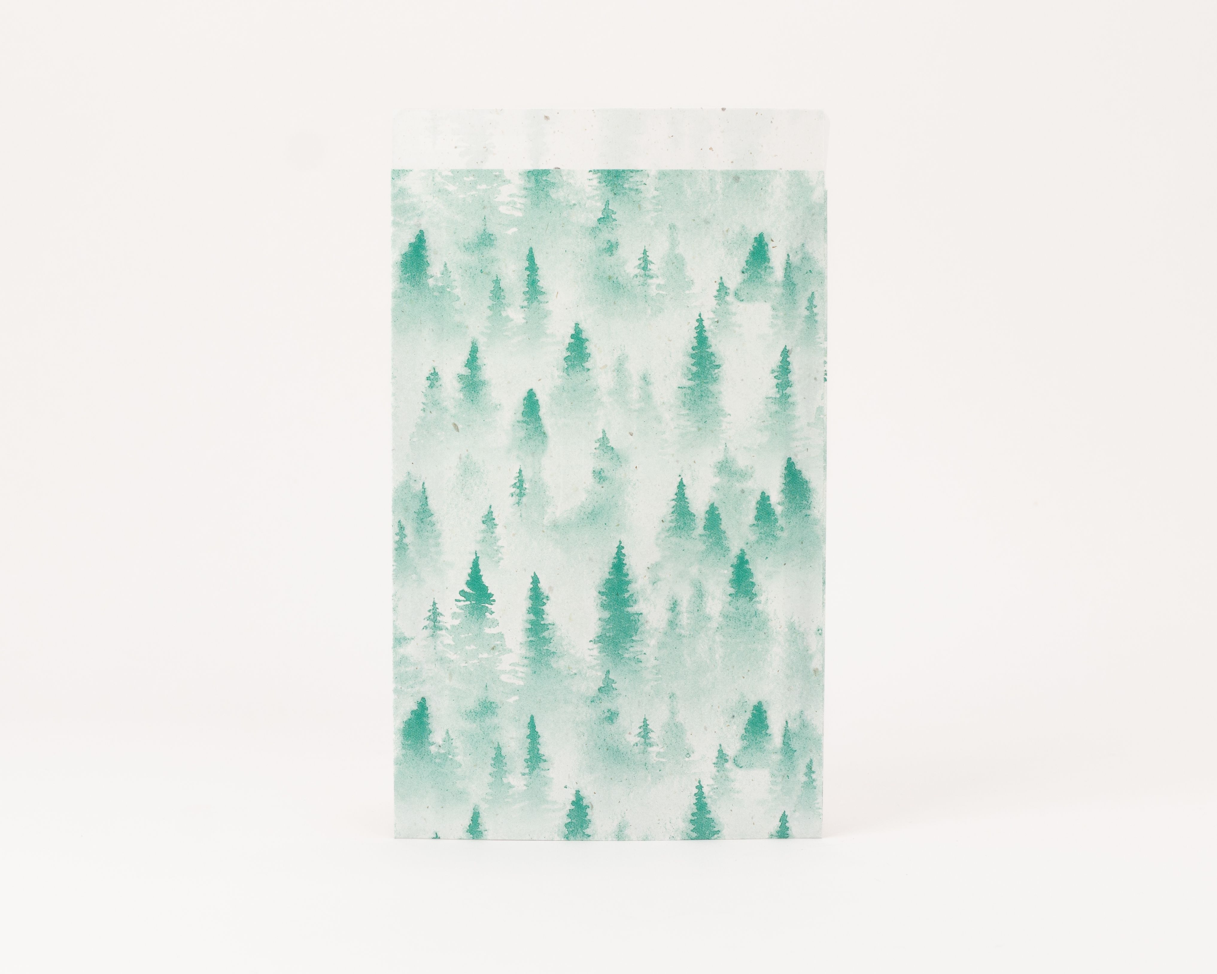 Flachbeutel mit nebeligem Tannenwald-Design in verschiedenen Grüntönen auf der Außenseite, die Innenseite ist hellbeige